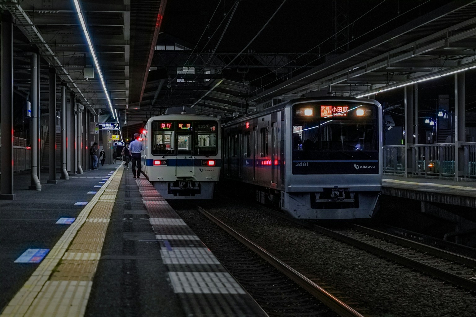 Due treni fermi in una stazione di notte con illuminazione
