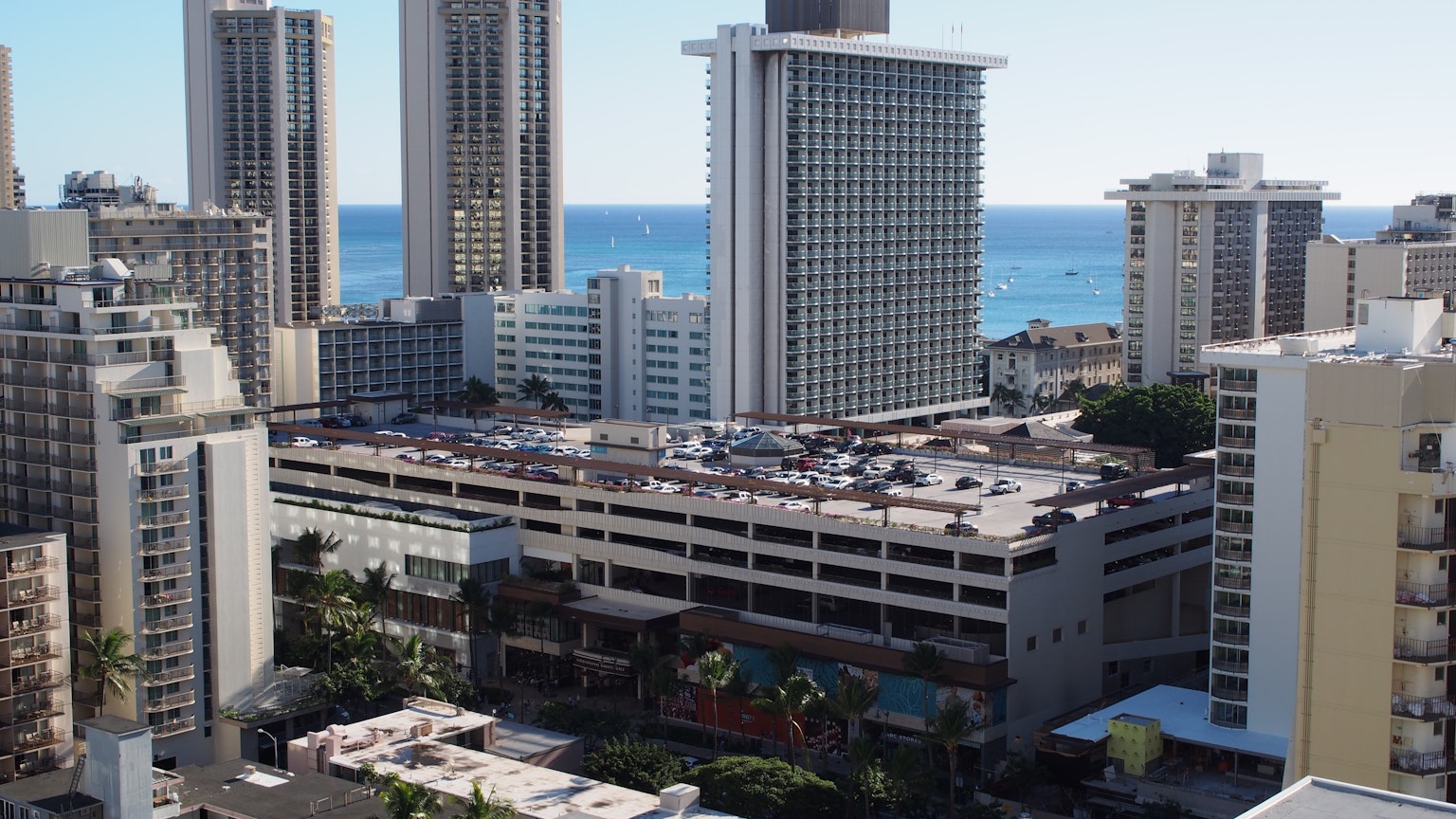 Vista de edificios altos con vista al océano y un estacionamiento