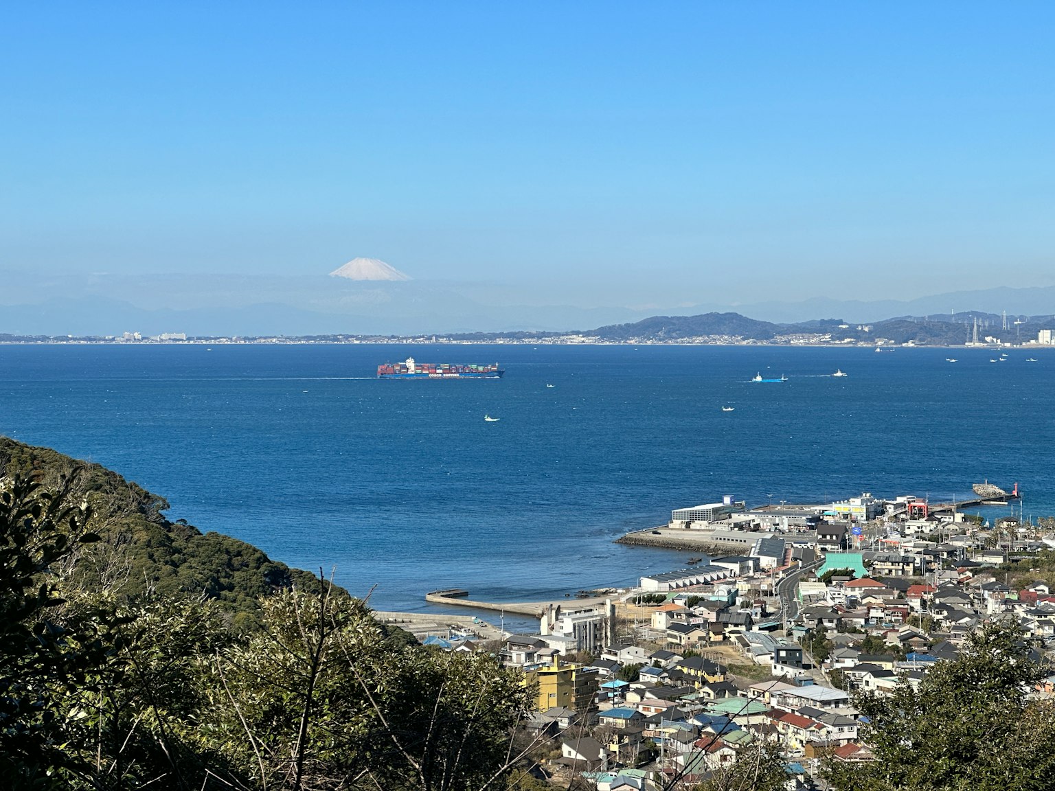 Vista escénica de una ciudad costera con océano azul y montañas distantes