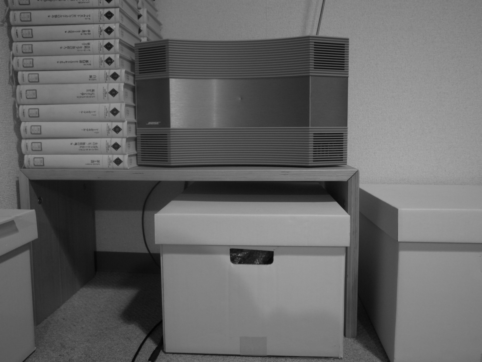 Black and white image of a storage box with a speaker on a shelf