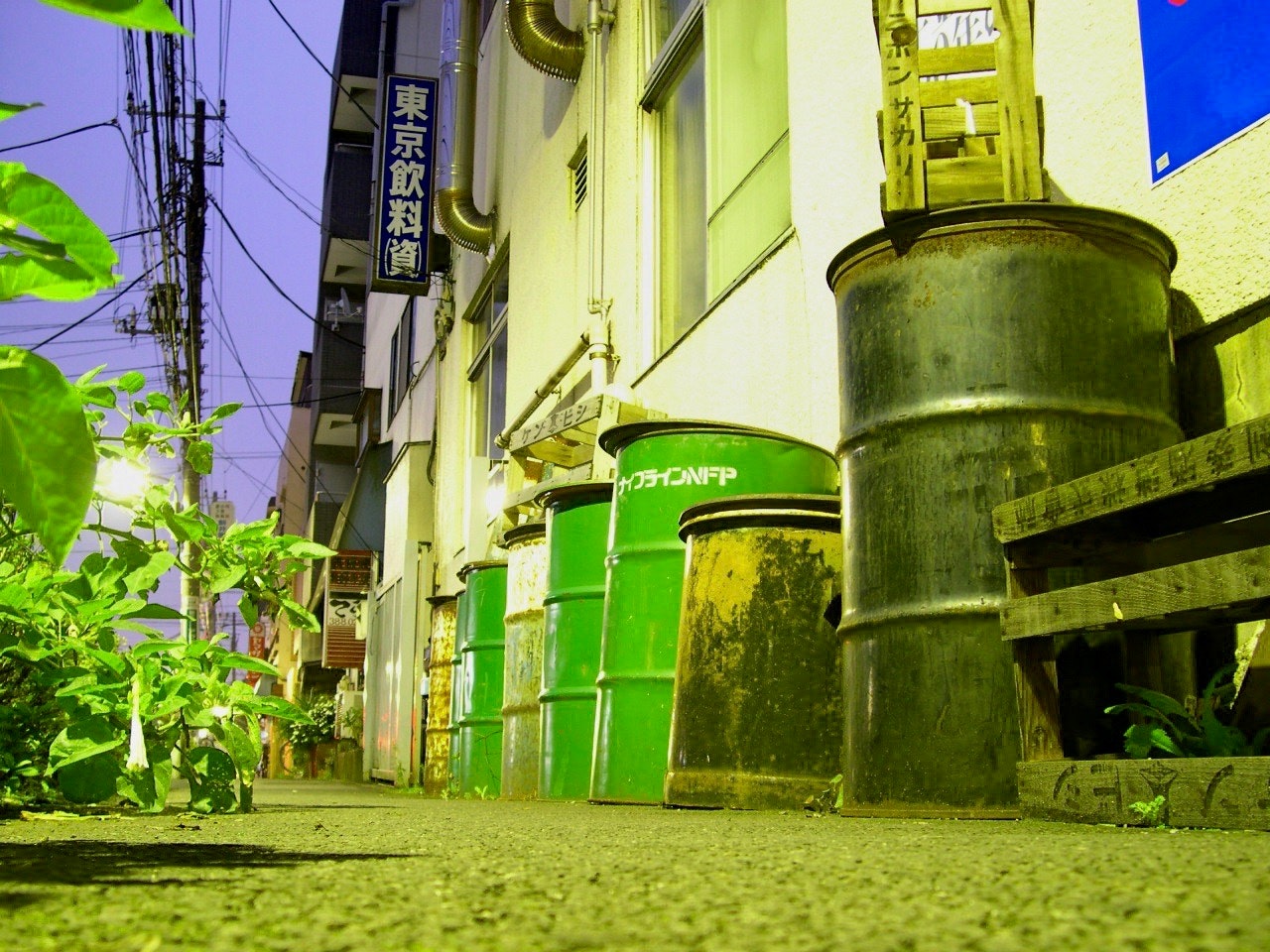 東京の深夜に光る路地の看板と緑の樽が並ぶ夜景