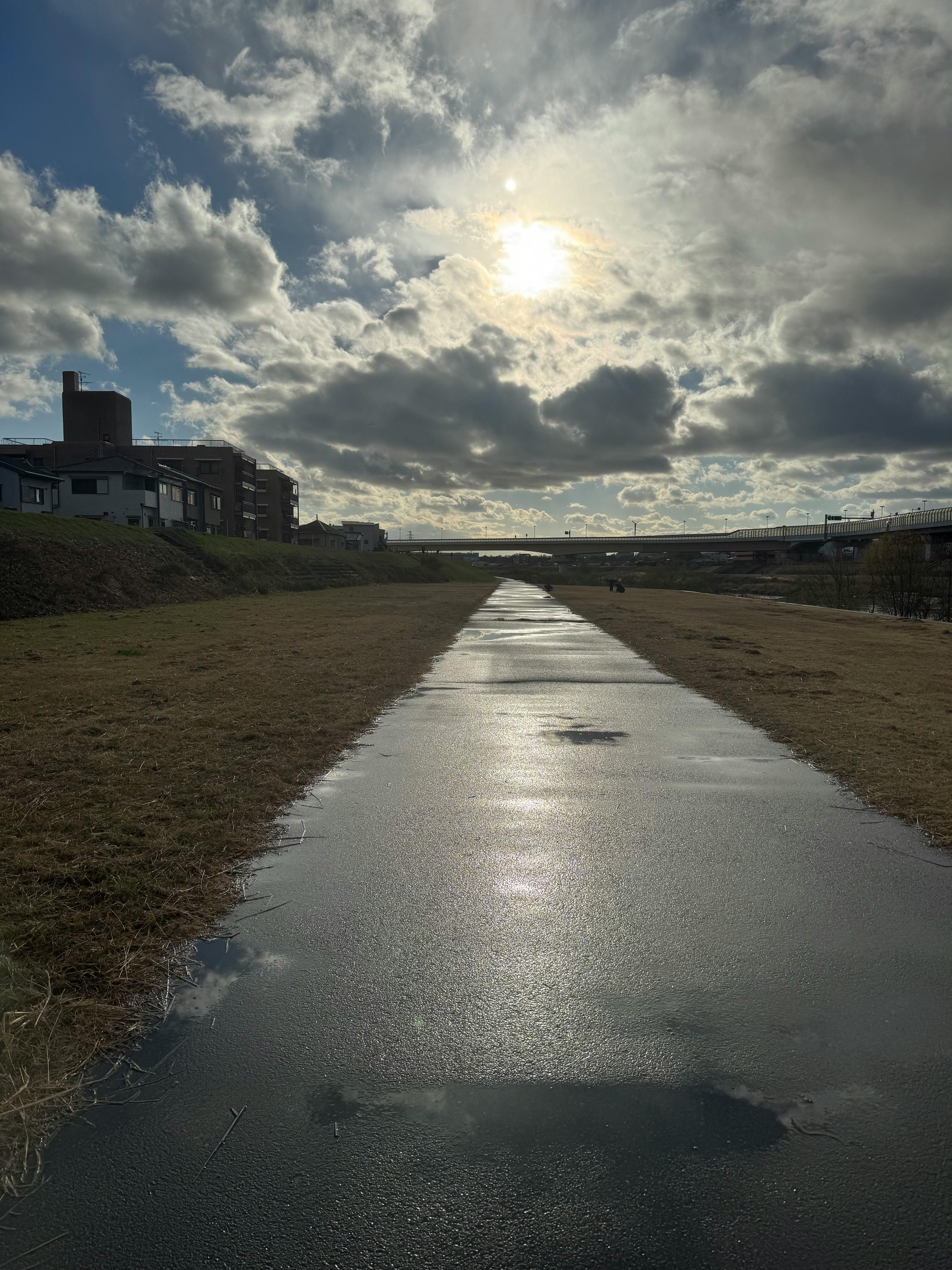 雨上がりの川沿いの遊歩道と雲の空