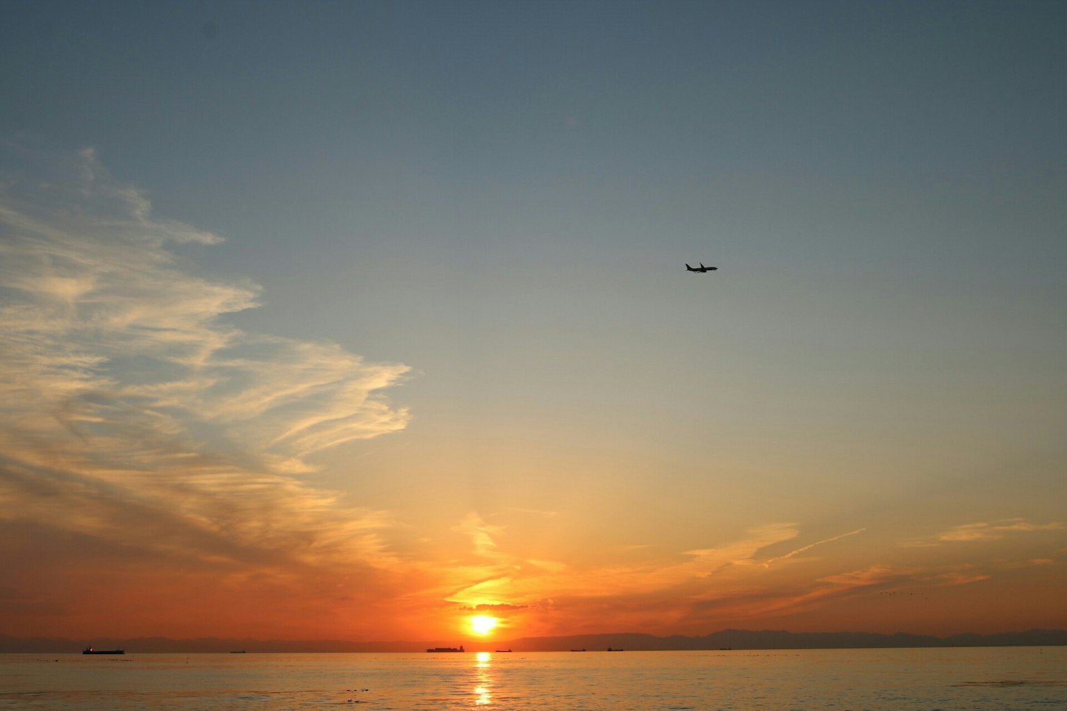 Bellissimo paesaggio del tramonto sull'oceano con un aereo nel cielo