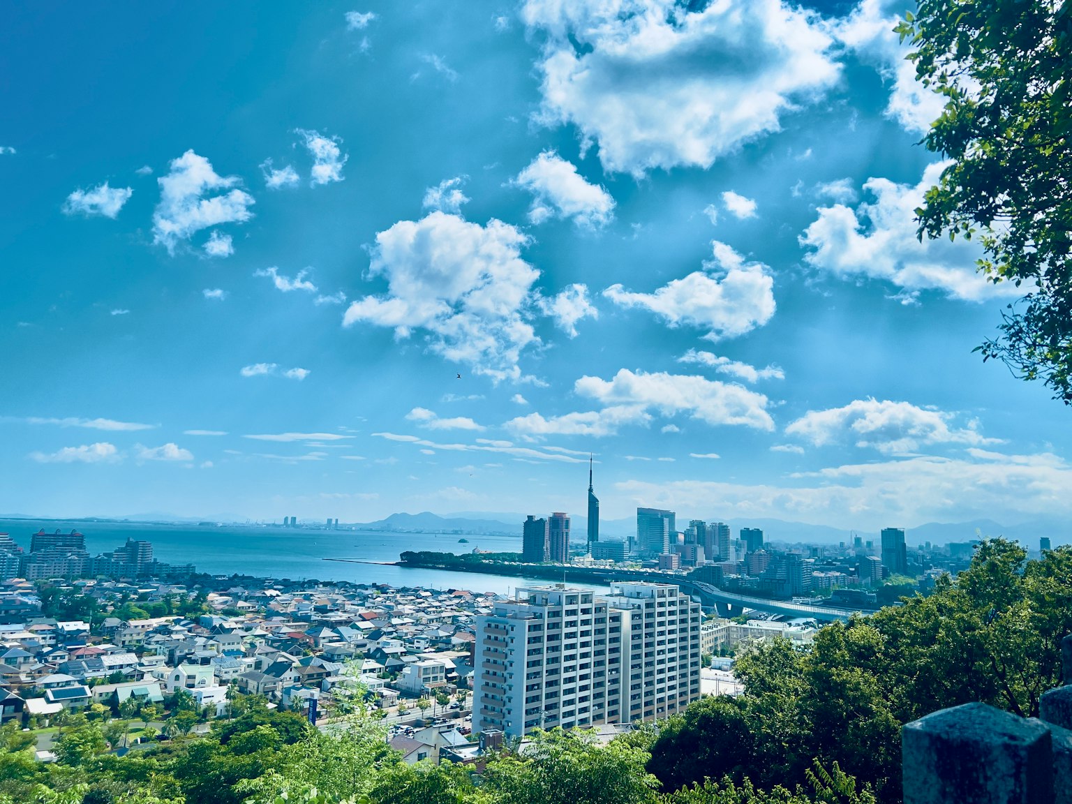 Cityscape with blue sky and clouds featuring sea and skyscrapers