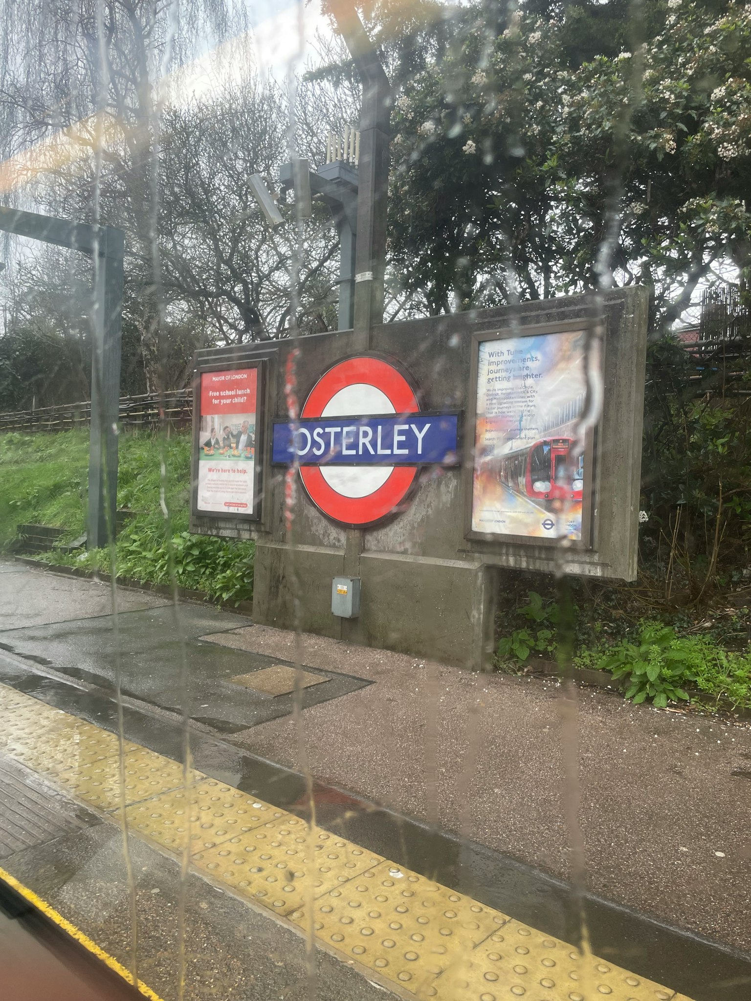 Señal de la estación de Osterley con anuncios en una parada de autobús