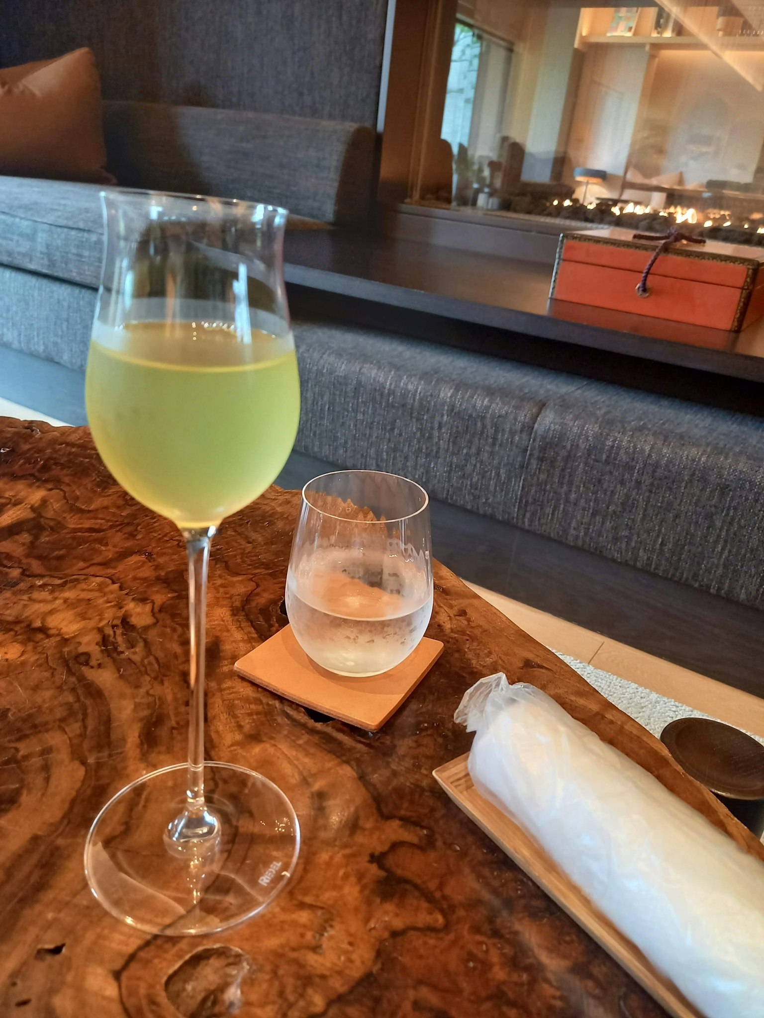 Un bicchiere alto con una bevanda verde e un bicchiere corto d'acqua su un tavolo di legno