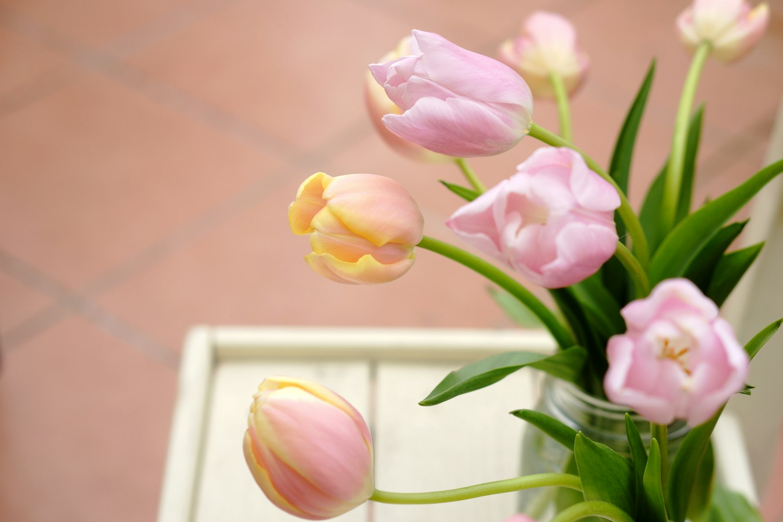 Un ramo de tulipanes rosas y amarillos en un jarrón de vidrio