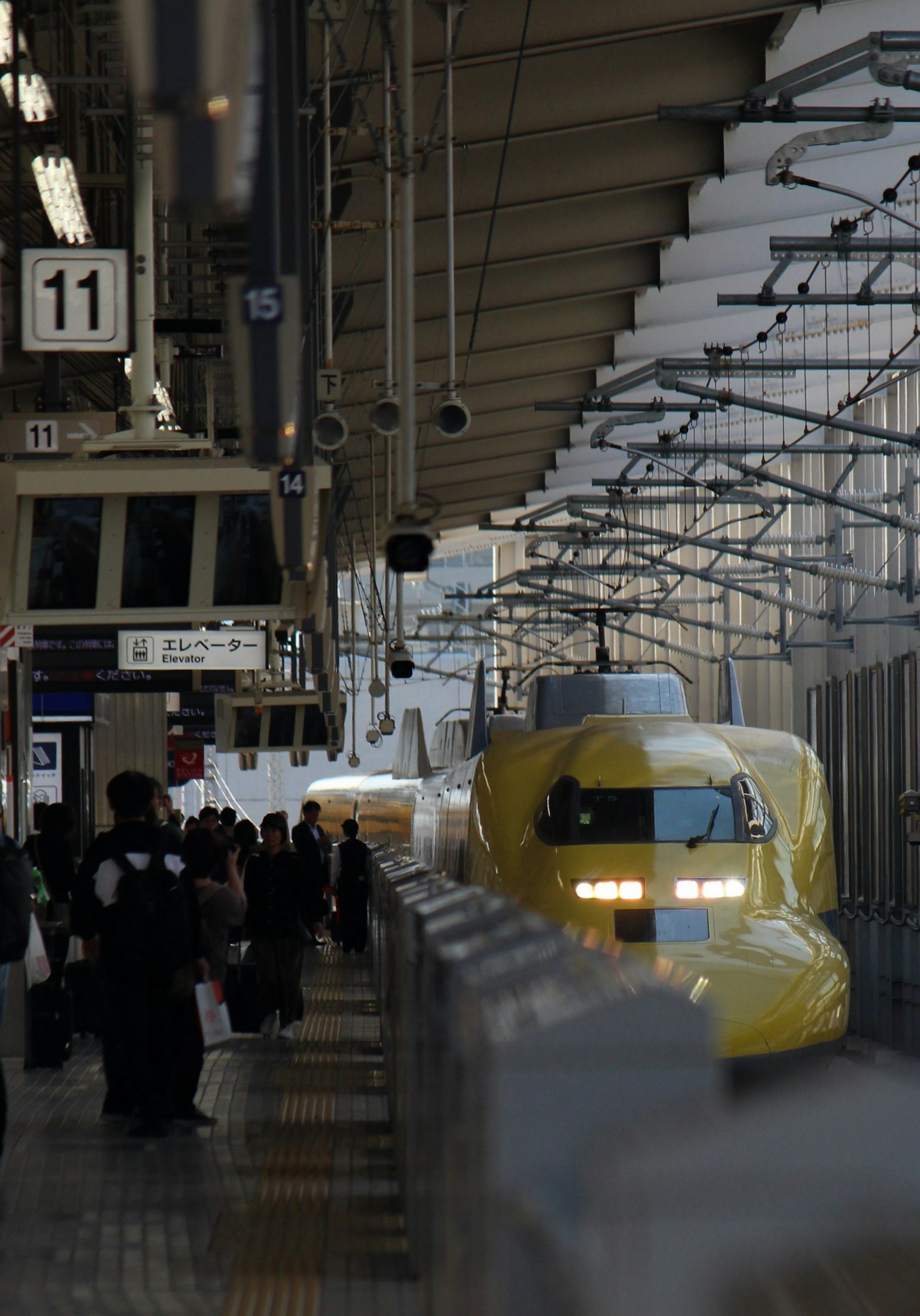 Yellow Shinkansen train at the station with passengers