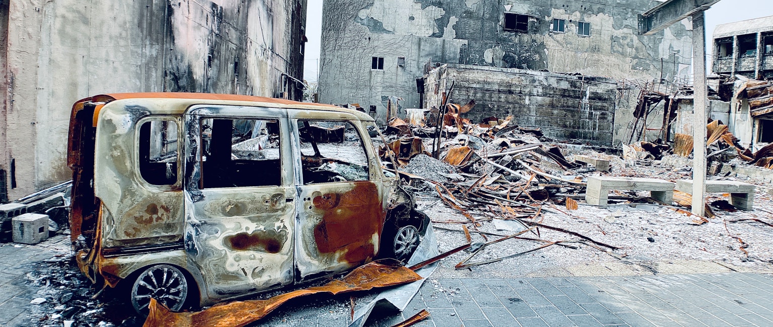 Paysage urbain en ruine avec un véhicule brûlé et des débris
