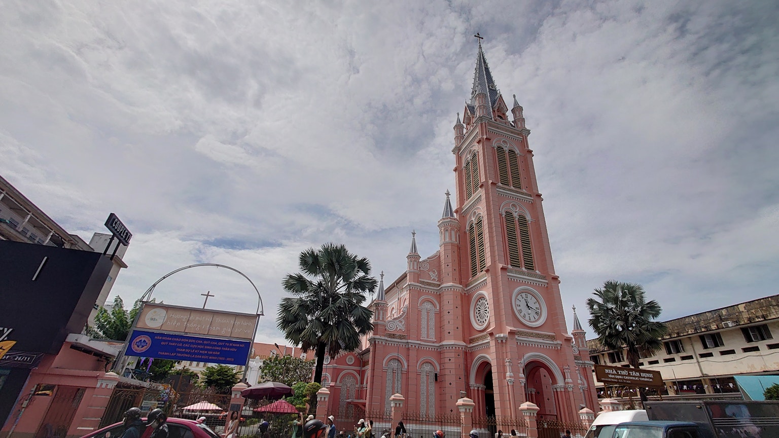 Menara gereja merah muda yang menonjol di lingkungan perkotaan yang hidup