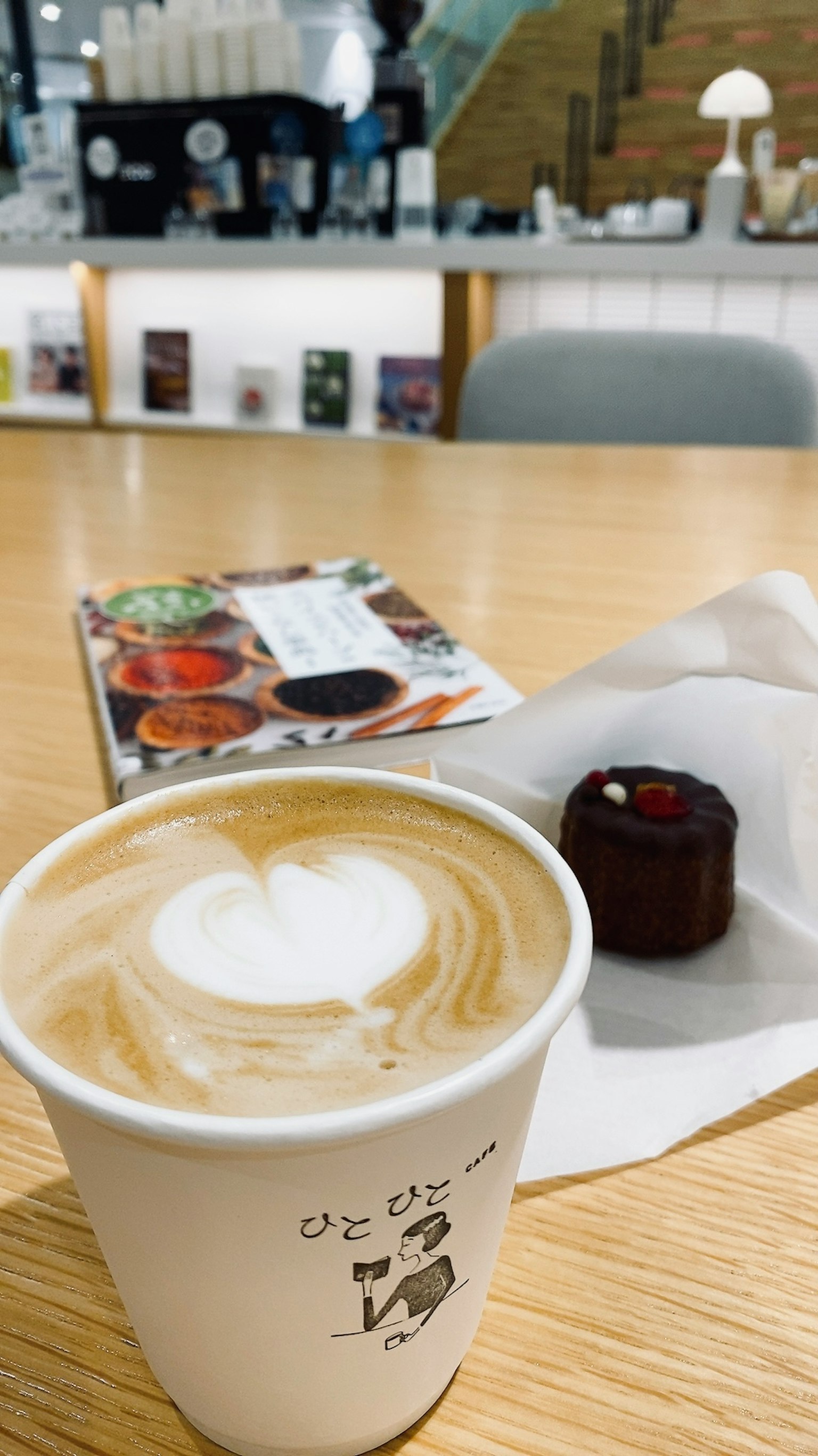 Cafészene mit einem Latte und einem kleinen Kuchen auf dem Tisch