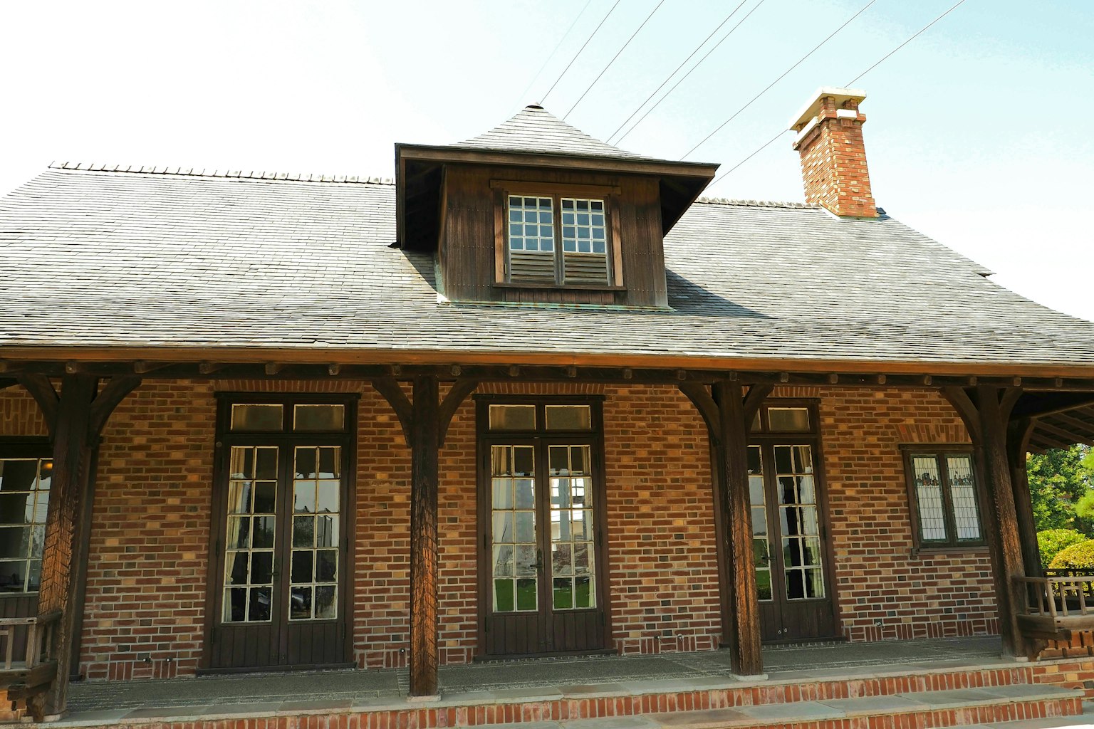 Exterior de una casa de ladrillo con techo de pizarra y columnas de madera