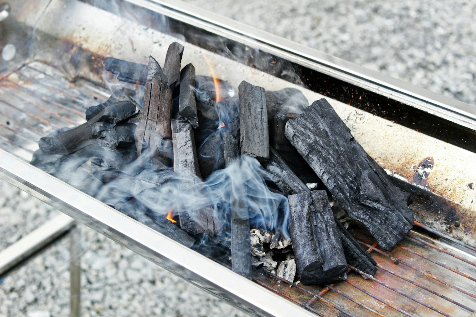 Arang terbakar di atas panggangan dengan asap yang naik