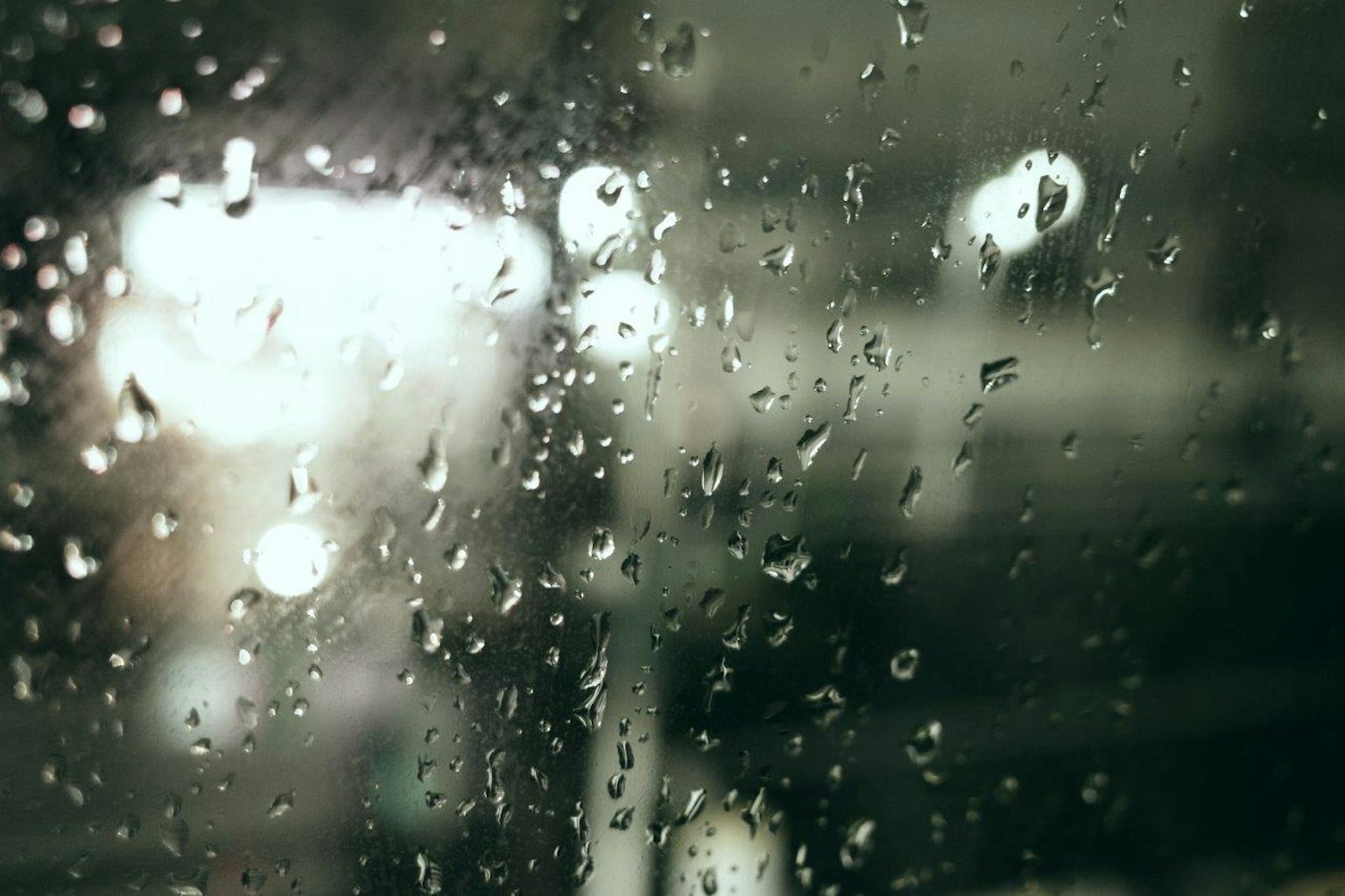 Verschommener Hintergrund durch ein Fenster mit Regentropfen