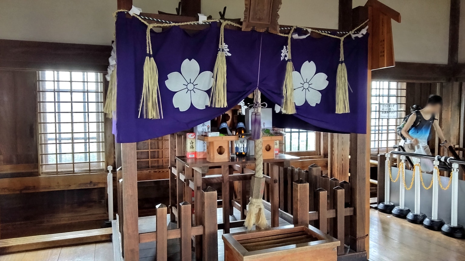 Altar de festival tradicional con tela morada y patrones de flores blancas en una habitación