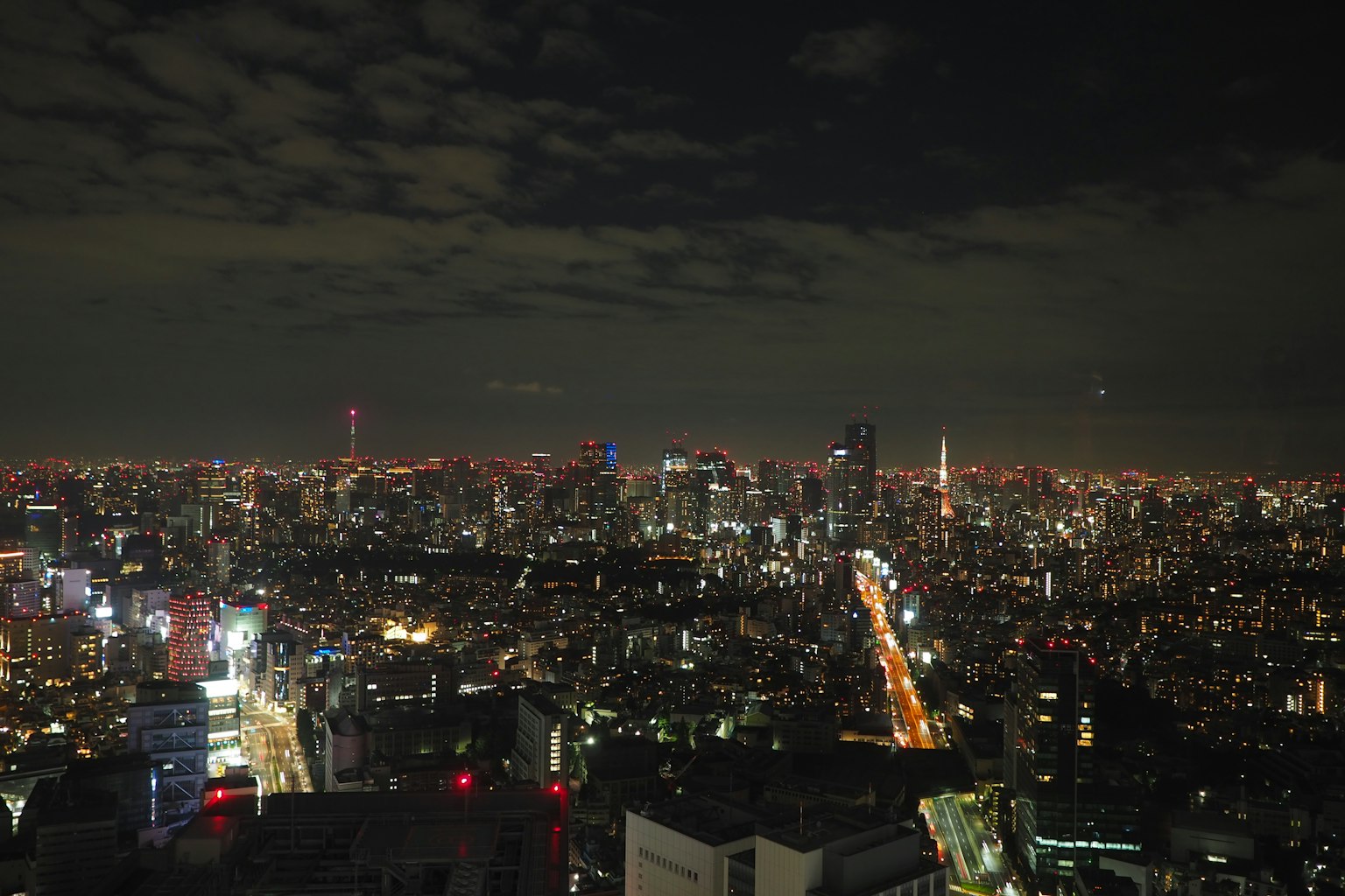 Tokyo skyline at night featuring illuminated skyscrapers and road lights