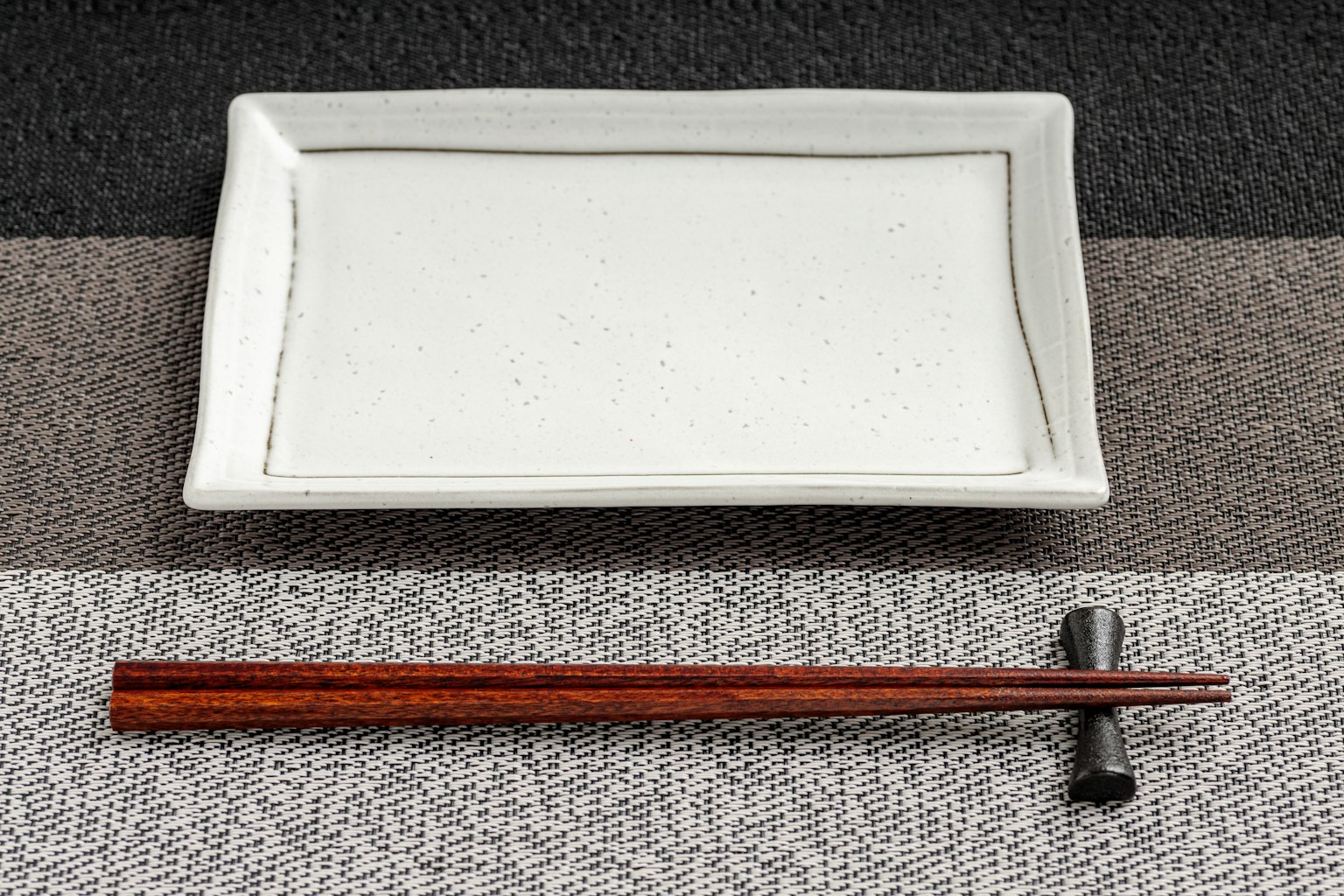 Une assiette rectangulaire blanche et des baguettes en bois posées sur une table