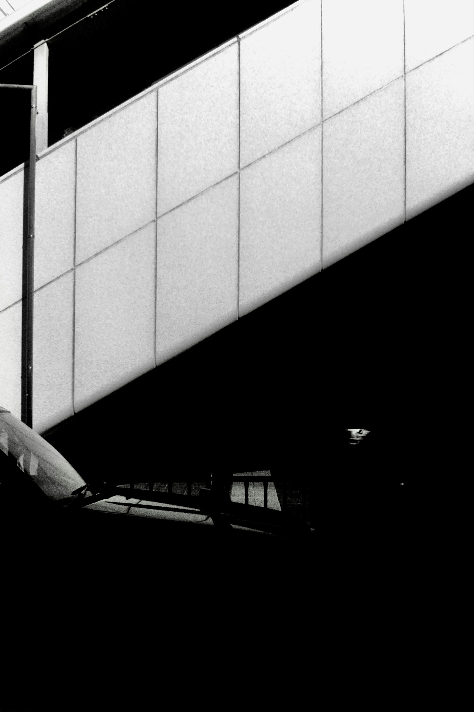 Black and white image showing the side of a building and part of a staircase