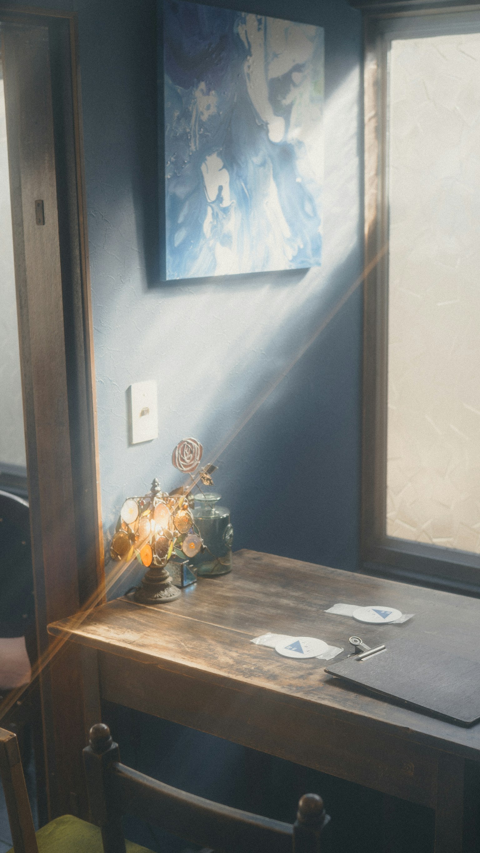 明るい光が差し込む部屋のテーブルに花のアレンジメントとアート作品がある