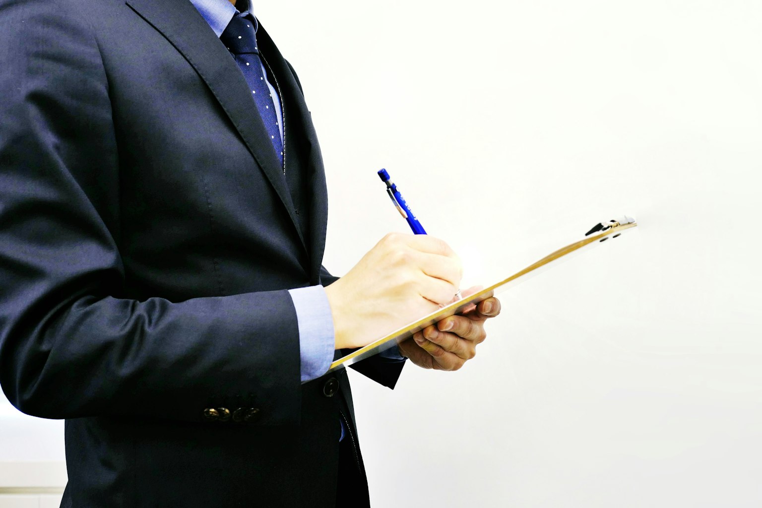 Un hombre con traje escribiendo en un clipboard