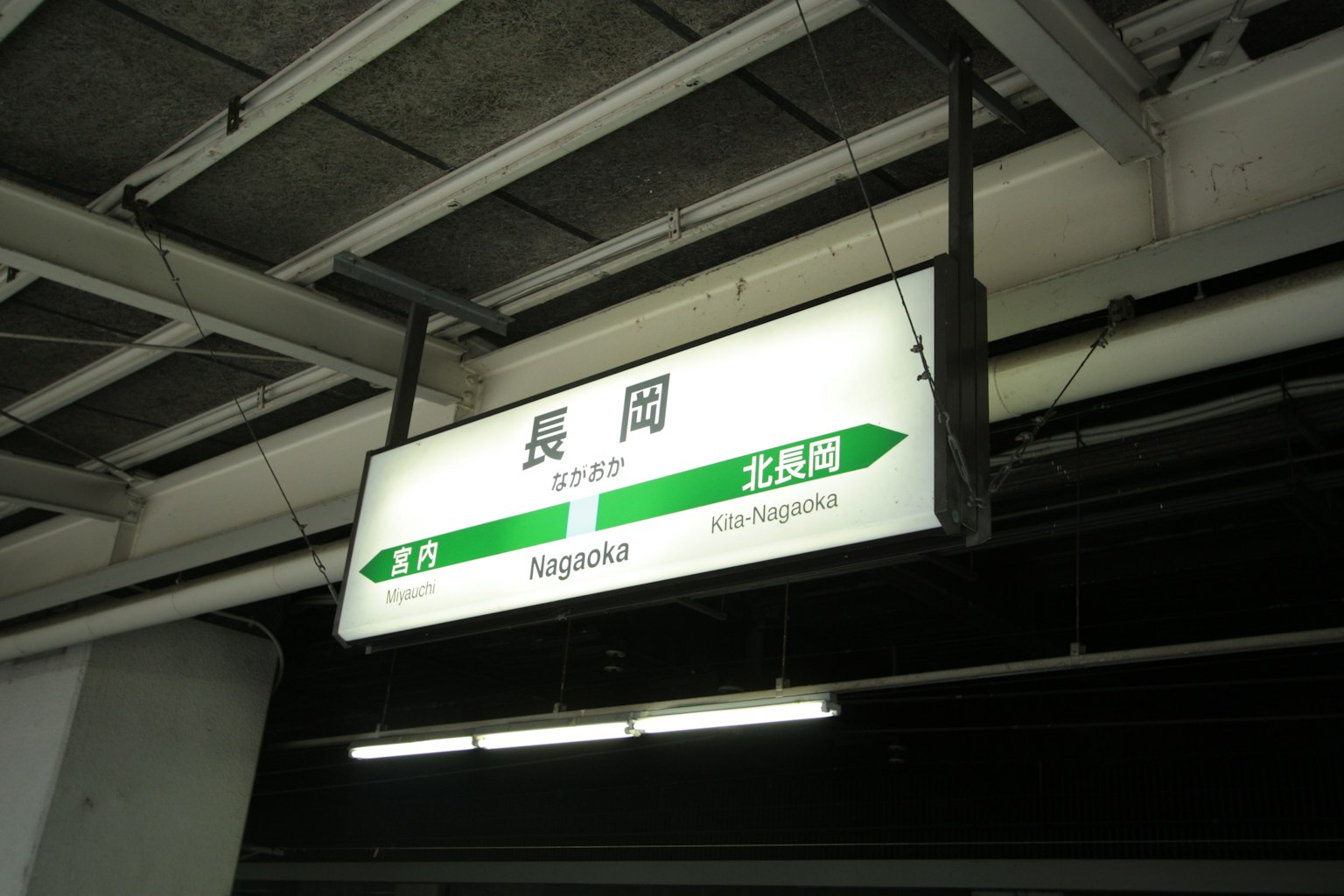 Papan tanda untuk Stasiun Nagaoka menampilkan arah kereta dan nama stasiun