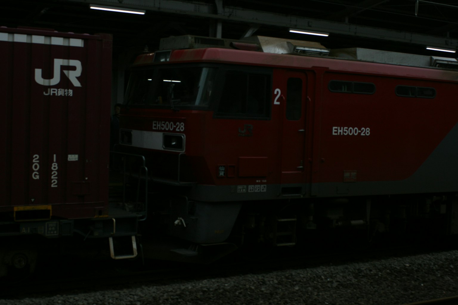 Kereta barang merah dan kontainer di stasiun malam