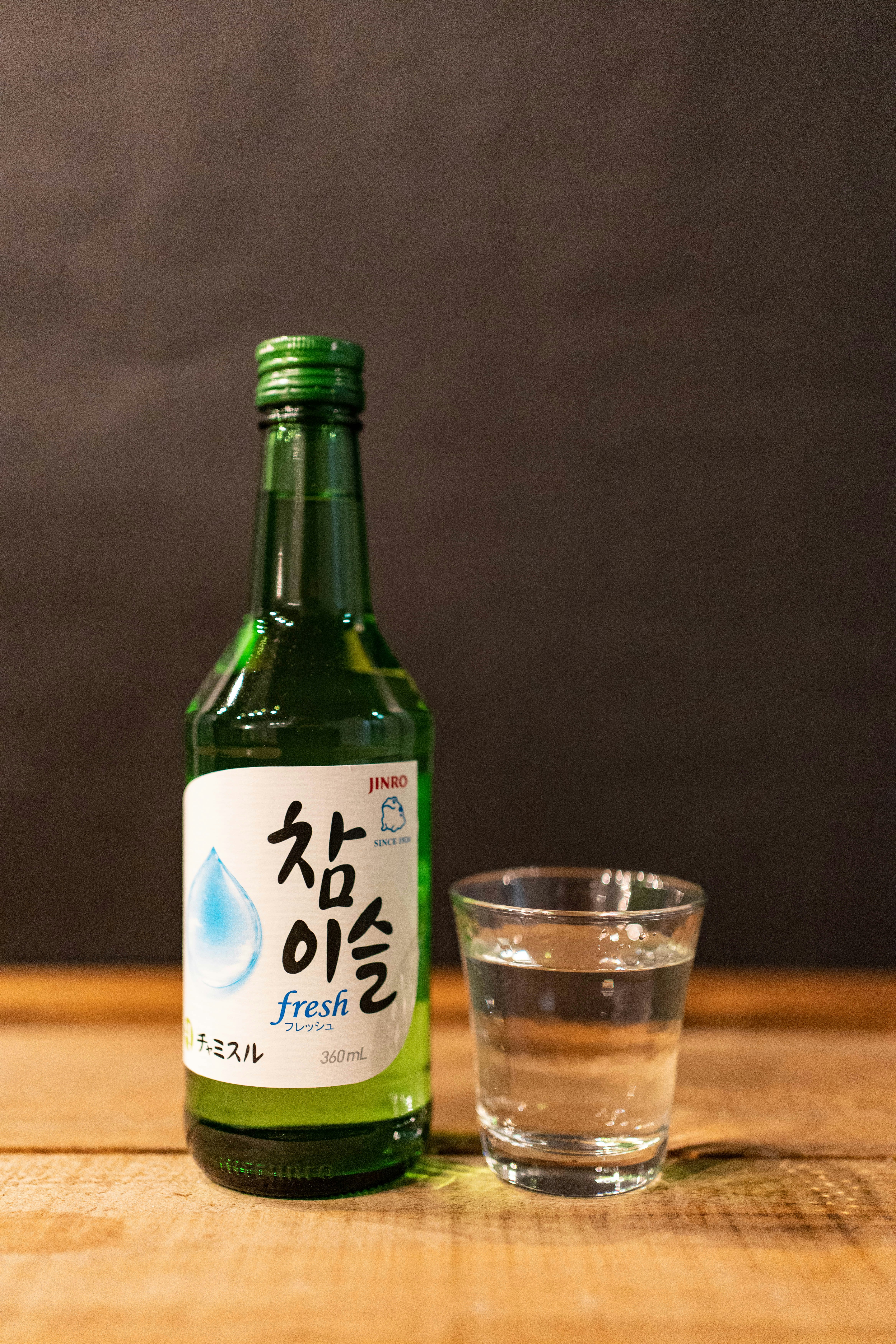 木のテーブルに置かれた韓国の飲料ボトルとグラス