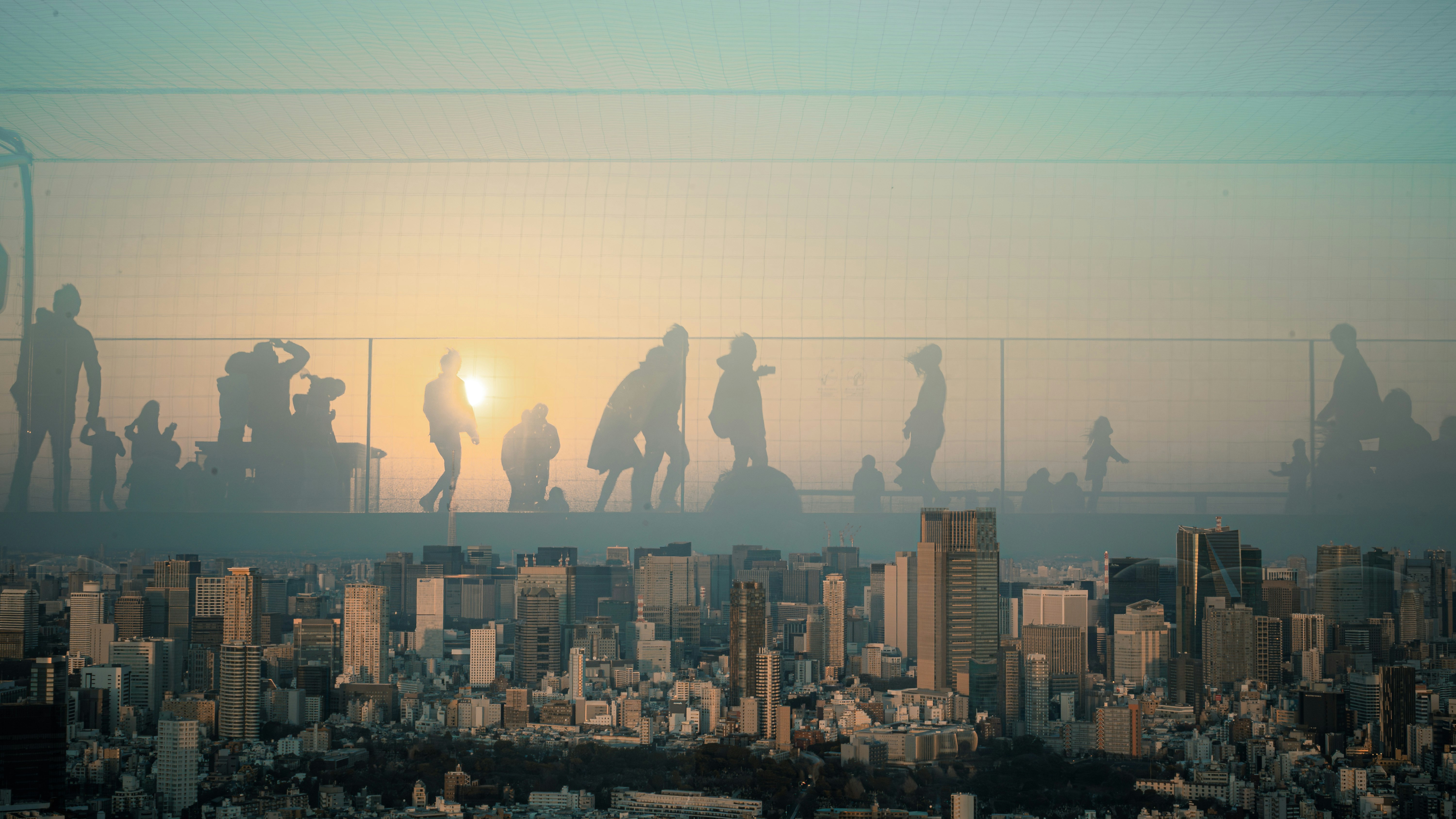 silhuetas de personas caminando con un horizonte urbano al atardecer