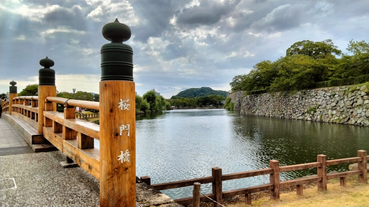 Vista panoramica sul fiume con un ponte in legno e un muro di pietra