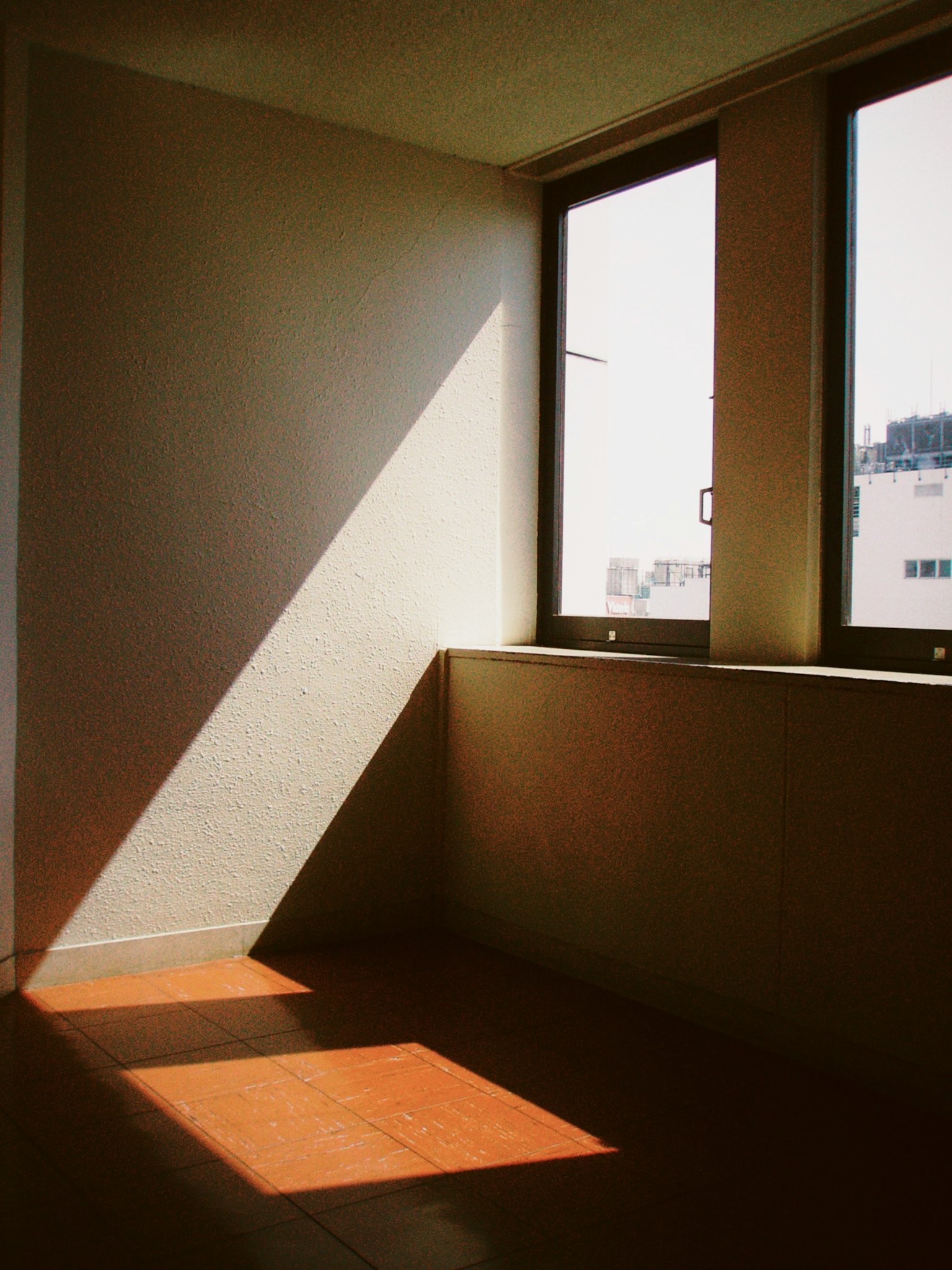 Một góc của căn phòng trống với ánh sáng mặt trời chiếu qua cửa sổ