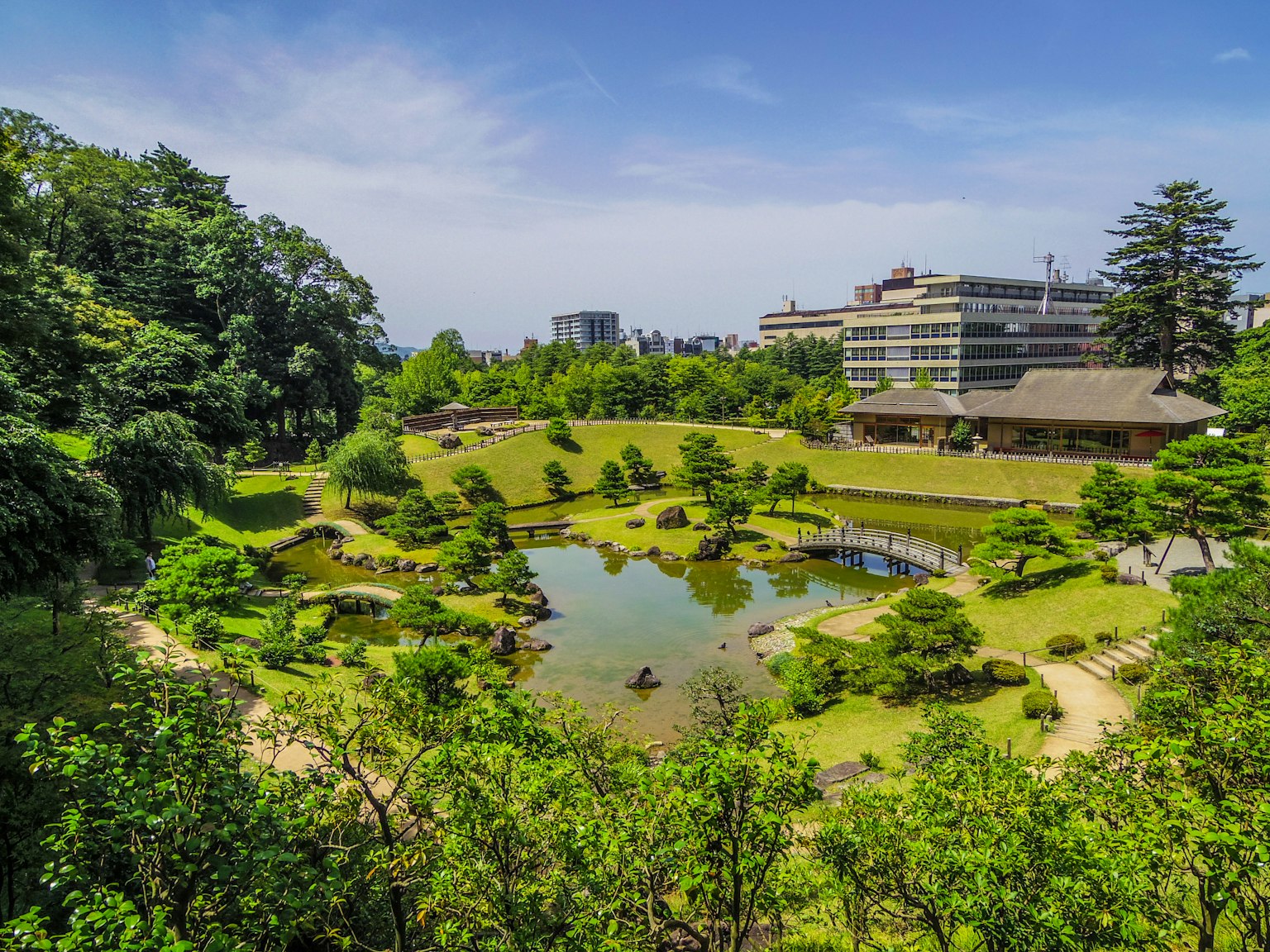 Paysage de jardin japonais luxuriant avec un étang et un bâtiment moderne