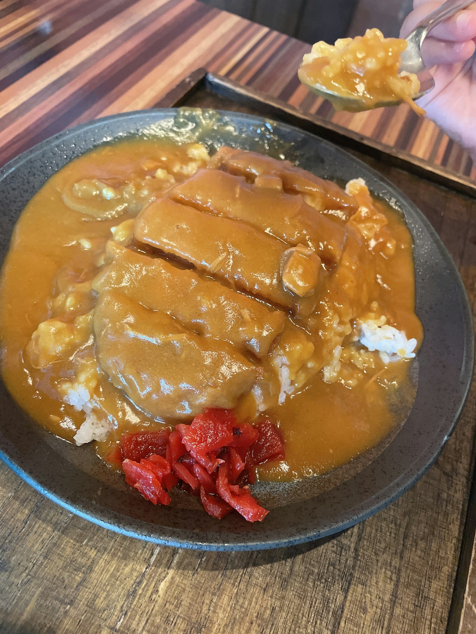 Plato de arroz cubierto con salsa de curry y chuleta de cerdo servido con kimchi