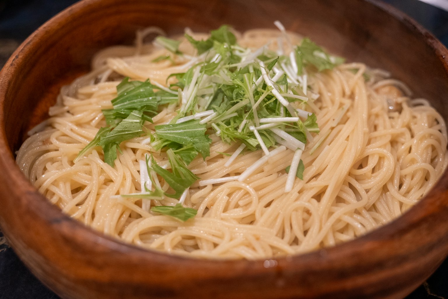 Spaghetti fumanti serviti in una ciotola di ceramica guarnita con cipollotti freschi