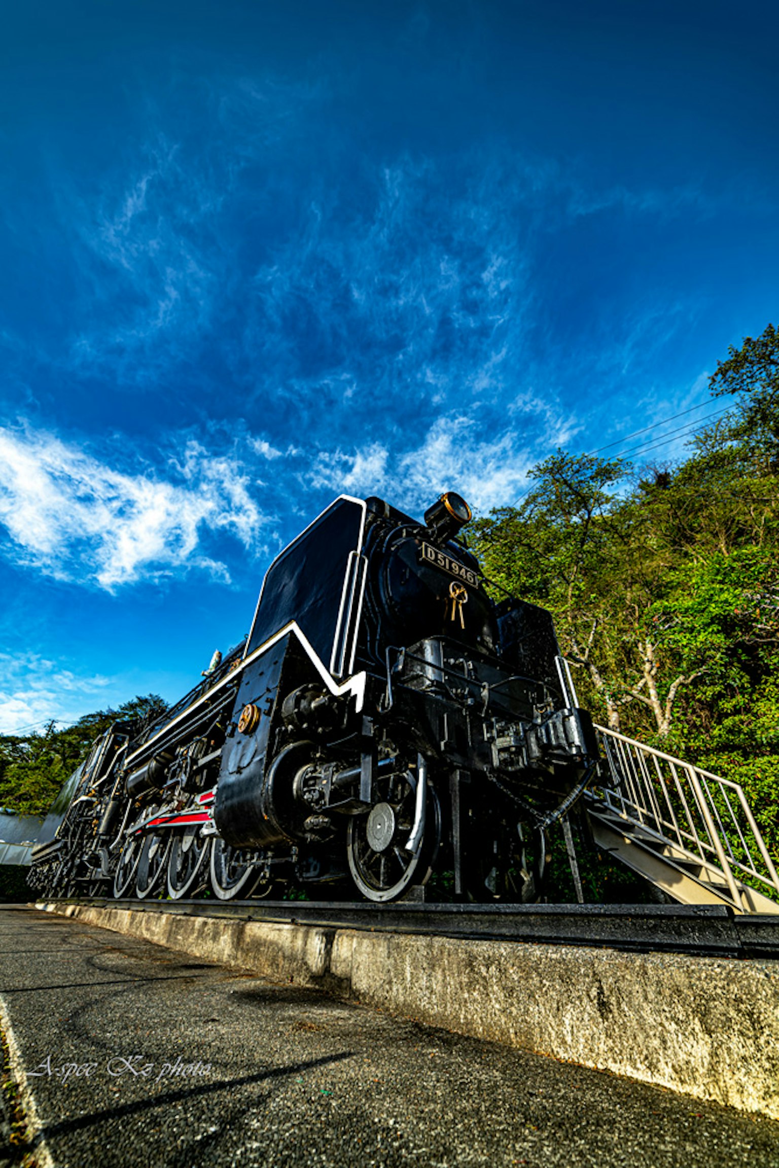 Black steam locomotive parked under a blue sky