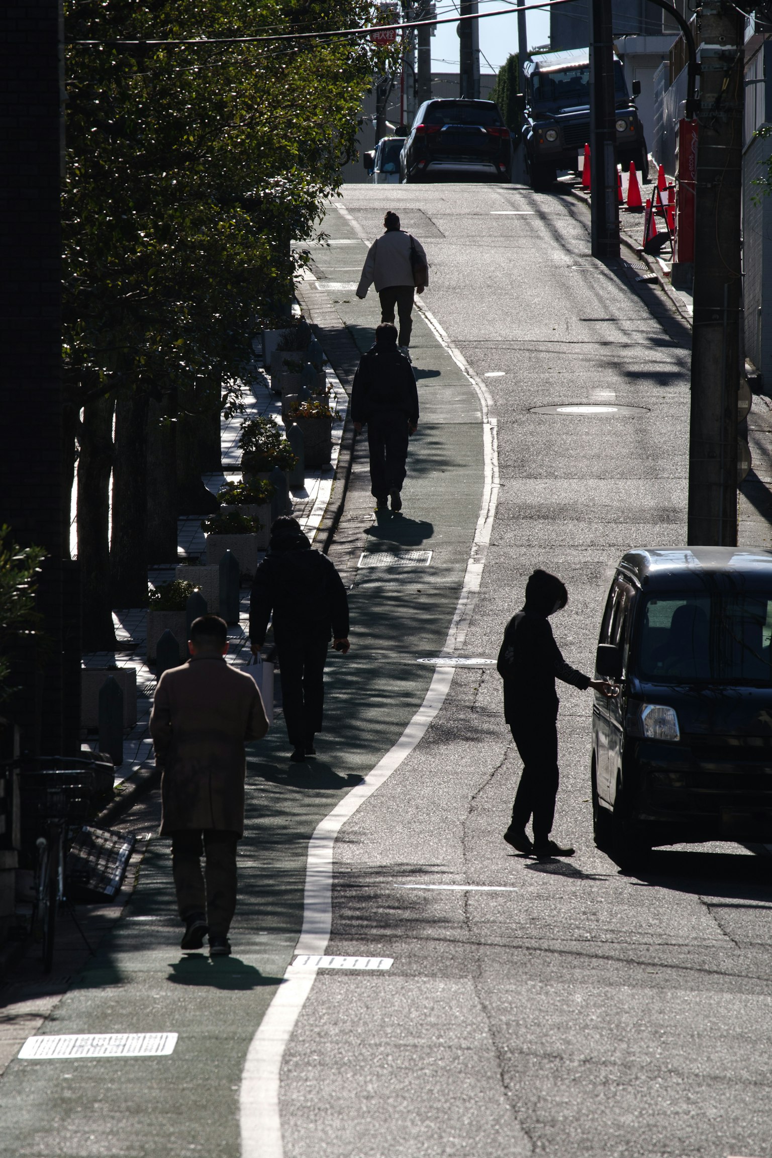 Des gens marchant dans une rue calme avec une voiture garée