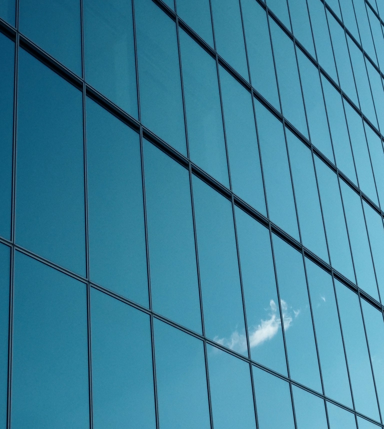 Riflesso di nuvole su una facciata di vetro blu di un edificio