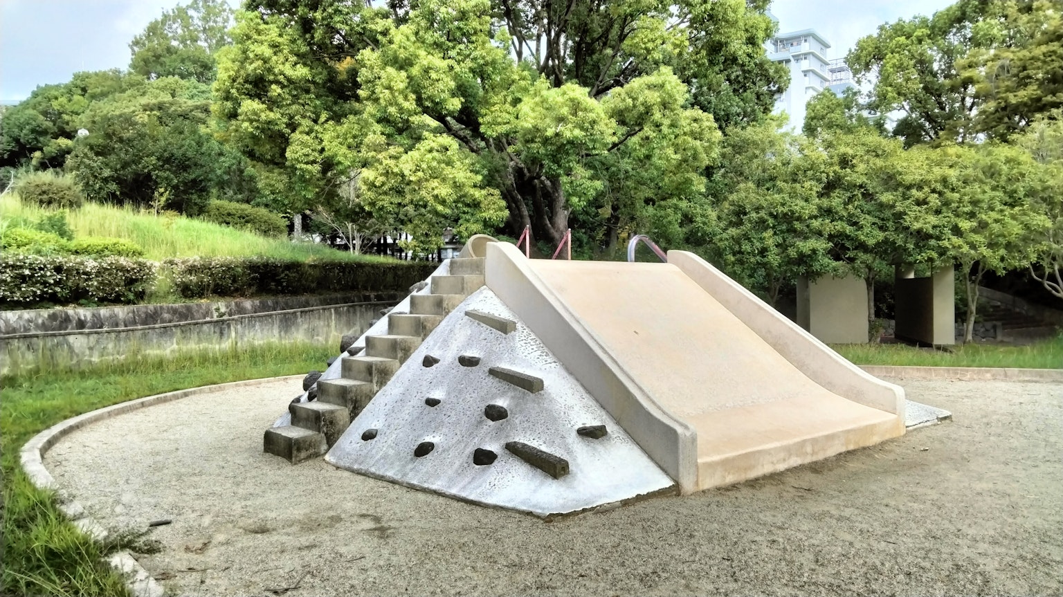 Peralatan taman bermain dengan seluncuran dan dinding panjat di taman