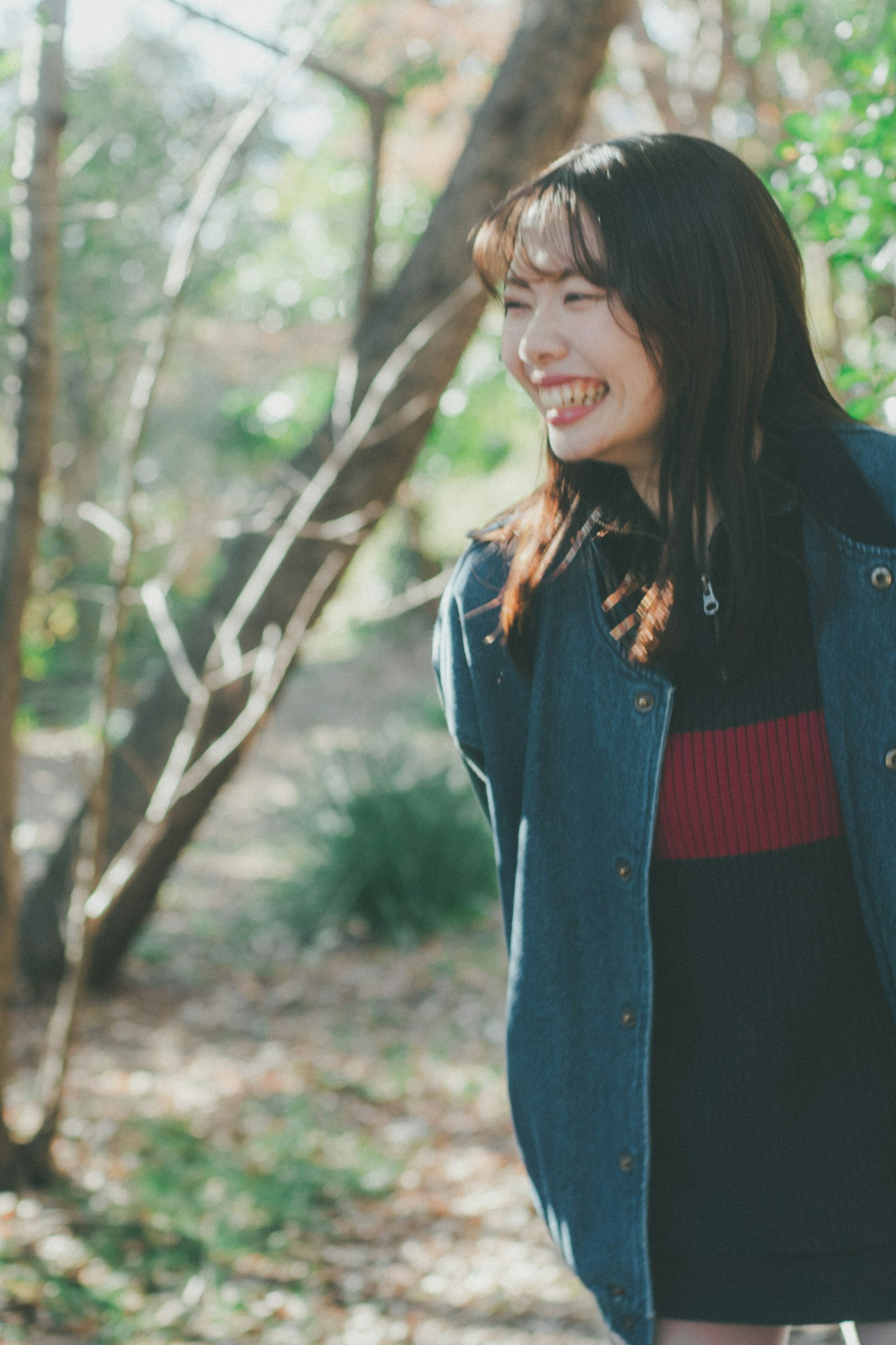 Smiling woman in nature with greenery and soft light wearing casual clothing