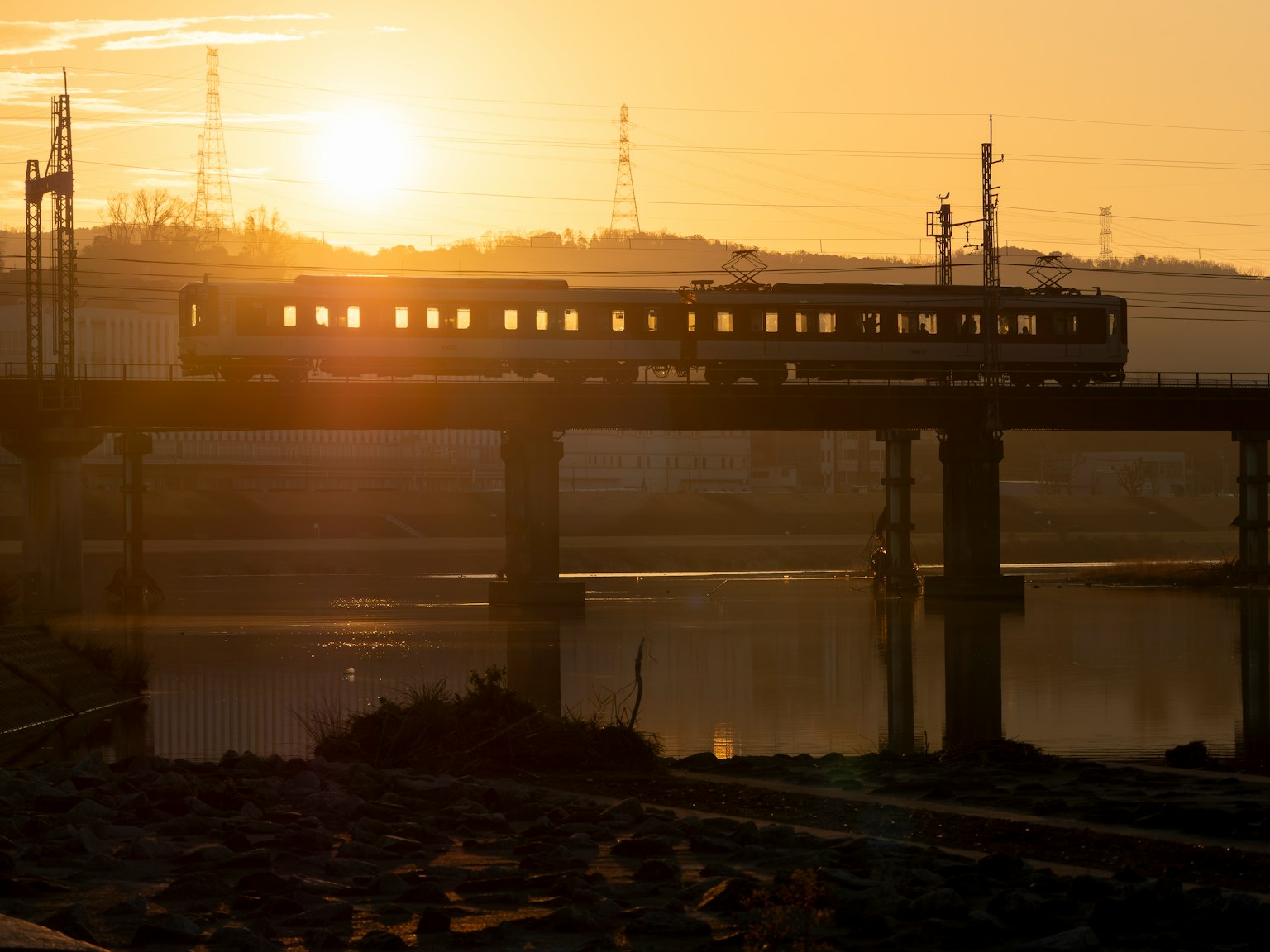 Silhouette di un treno che attraversa un ponte ferroviario al tramonto