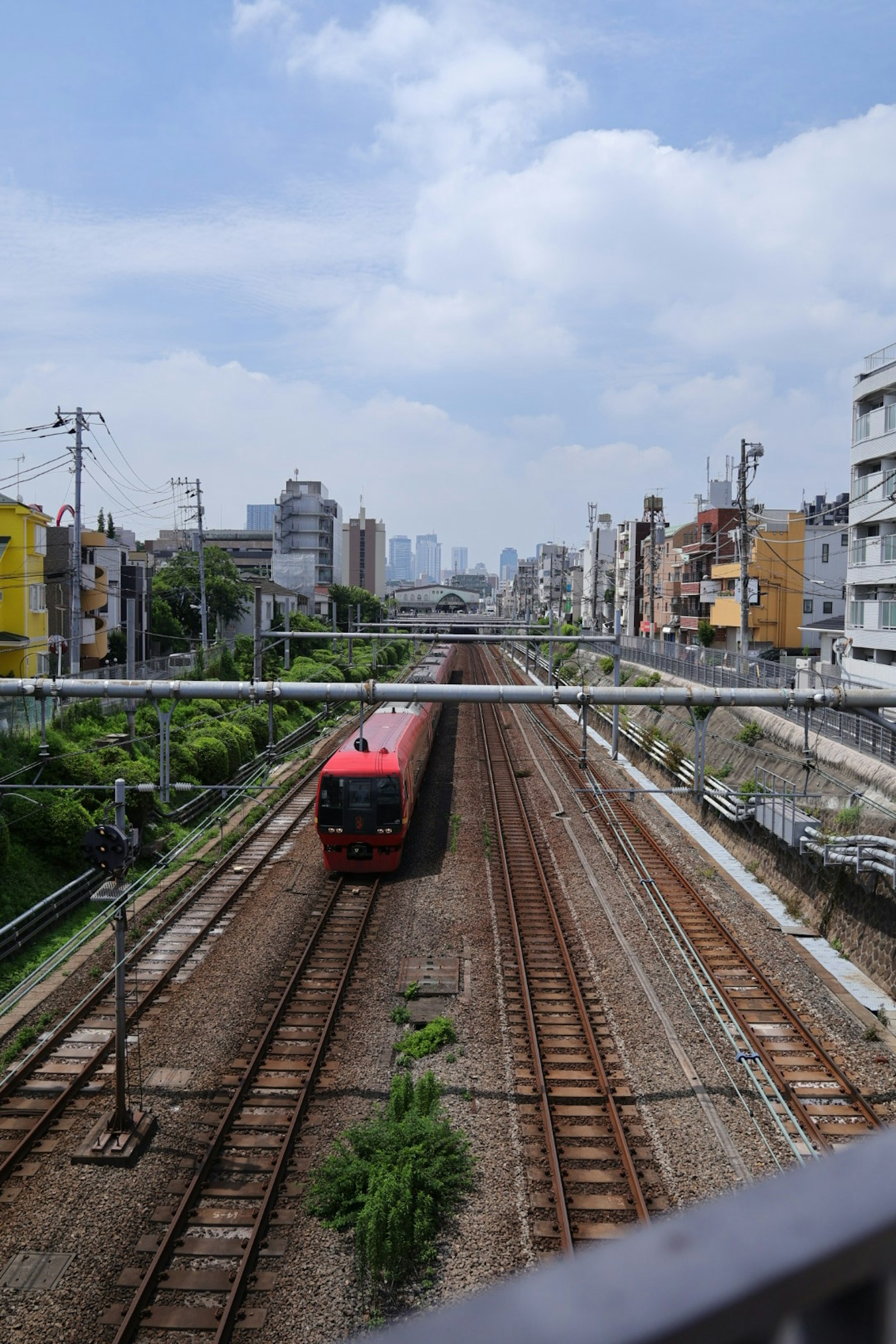 Red train running along railway tracks in an urban landscape