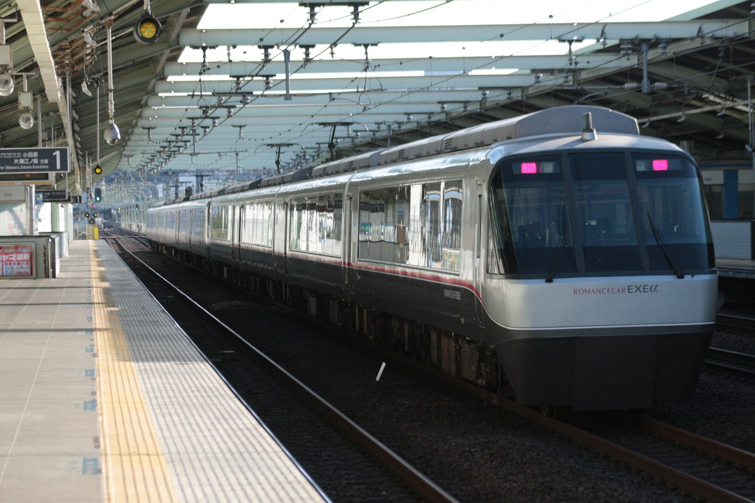 Train moderne arrêté à une station sous un toit lumineux avec plateforme ferroviaire