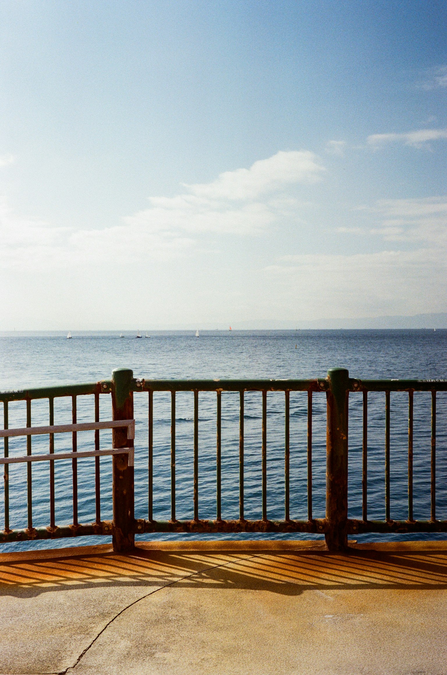 Malersicher Blick auf ruhiges Meer und blauen Himmel mit sichtbarem Geländer