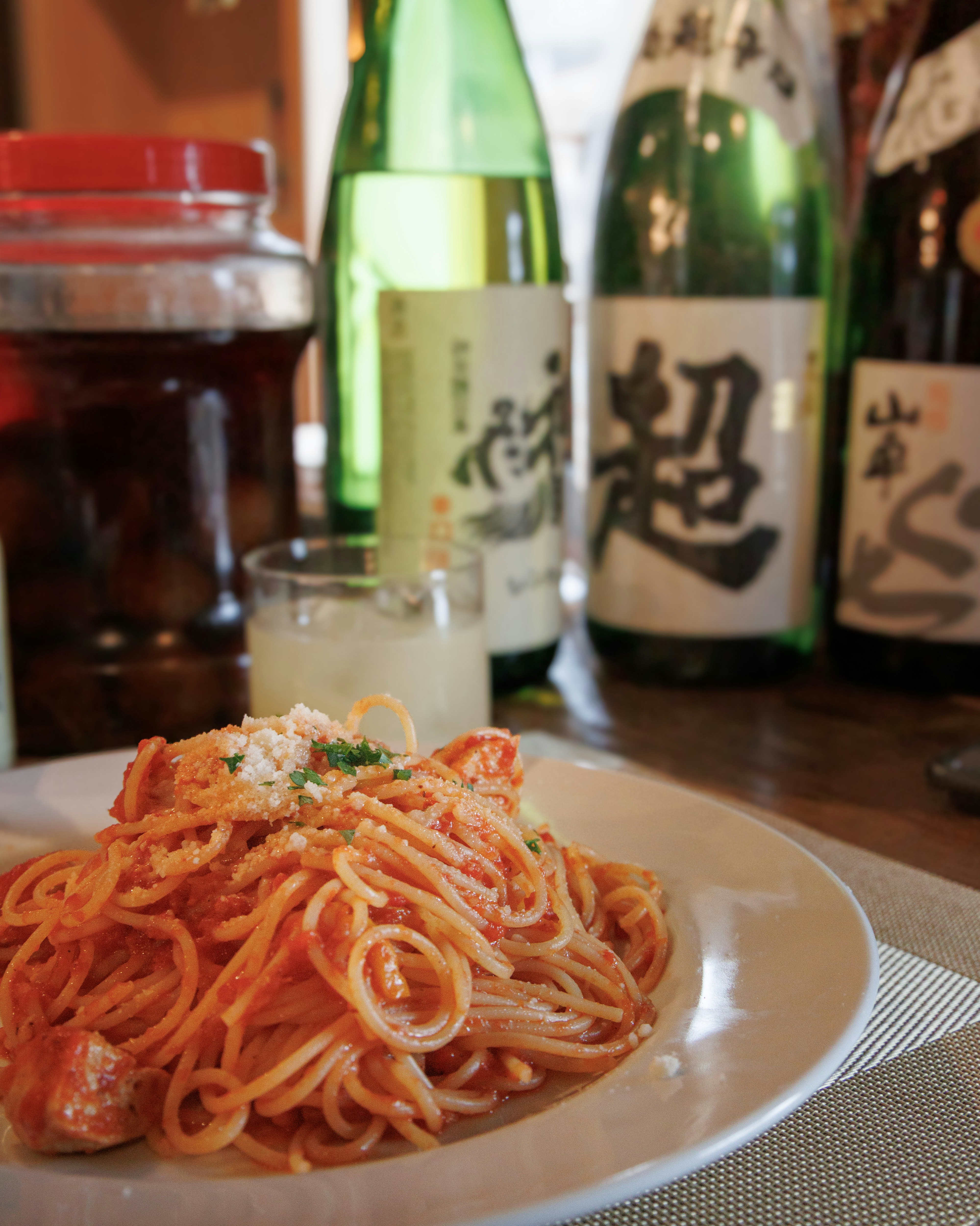 赤いトマトソースのスパゲッティと日本酒の並ぶ食卓