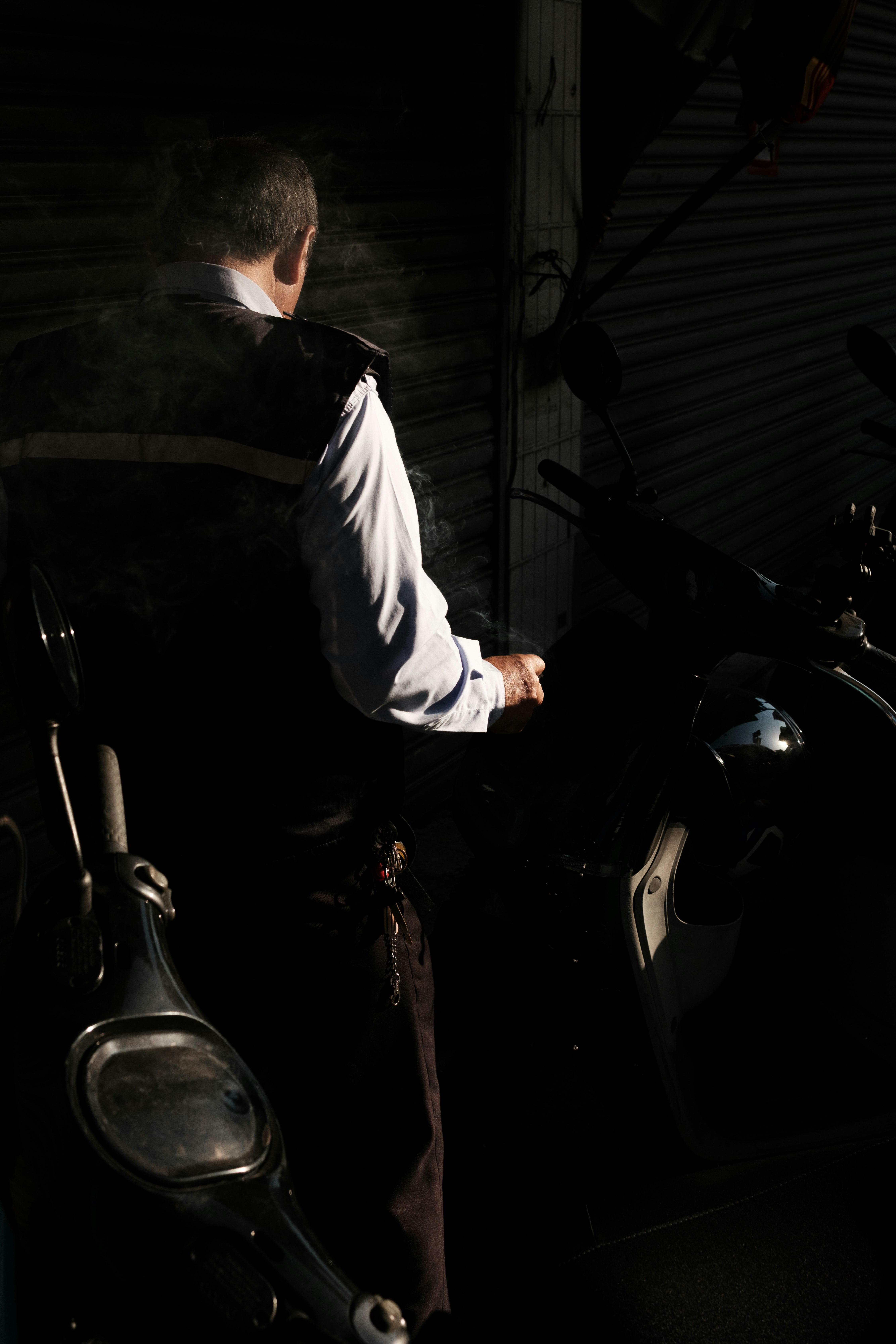 暗がりでバイクの横に立つ男性