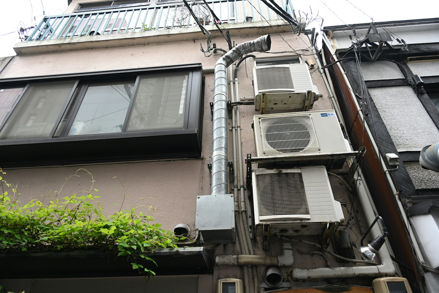 Unités de climatisation et conduit d'évacuation fixés à la façade d'un bâtiment