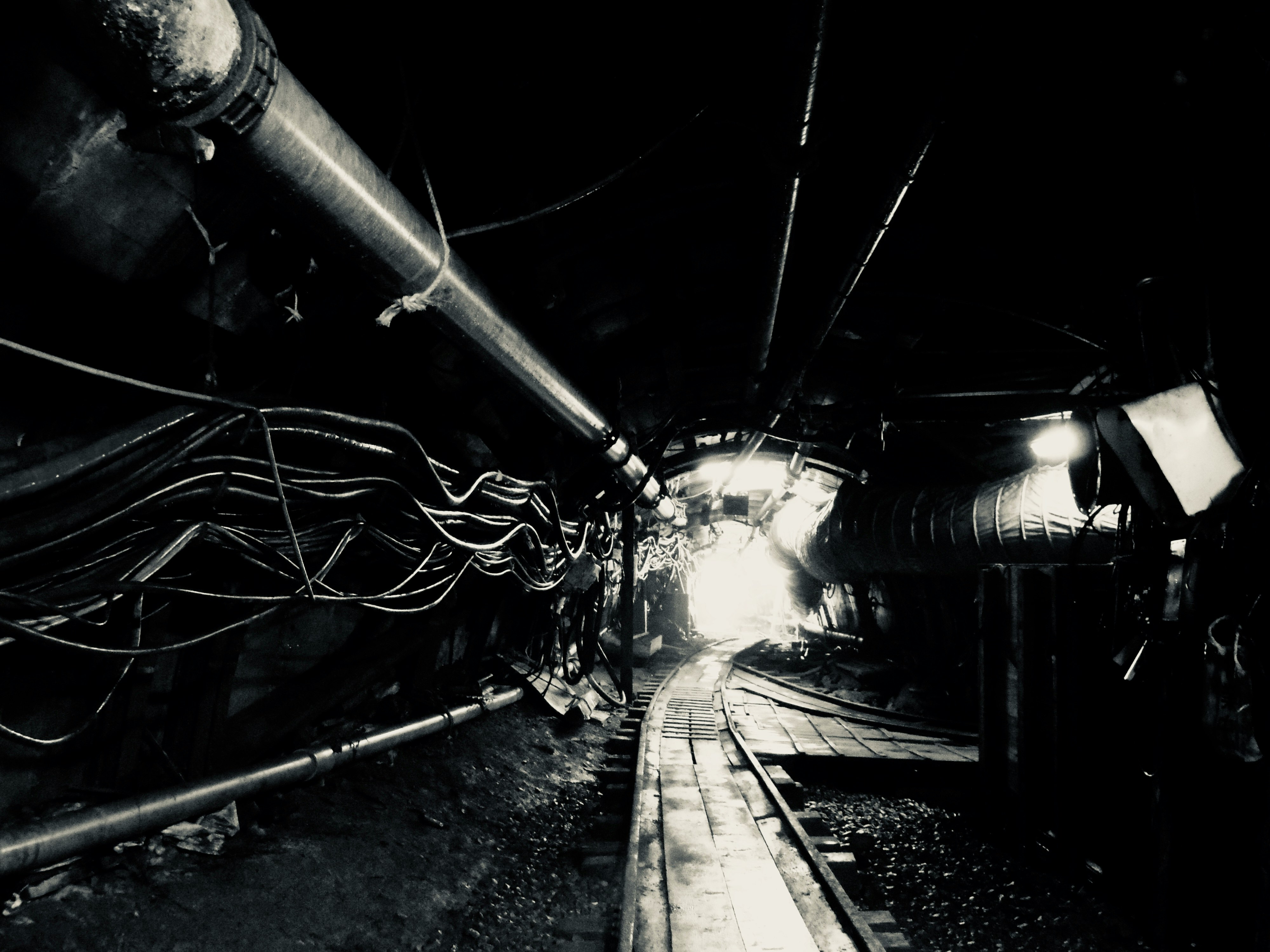 暗いトンネル内の配管と線路の奥行き