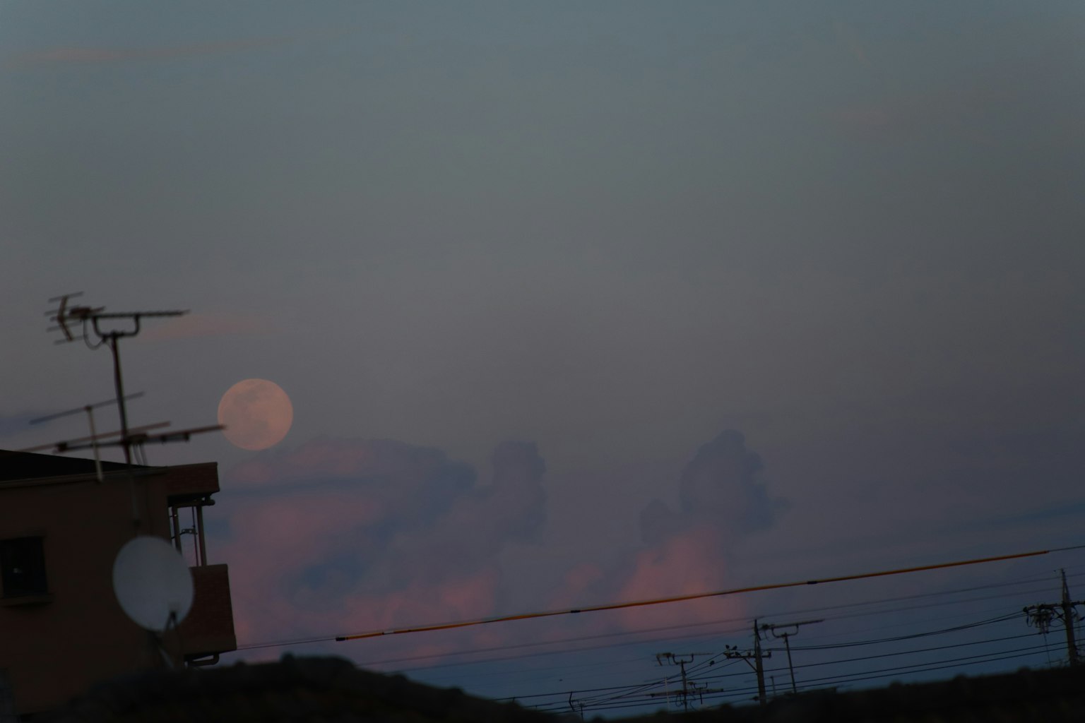 Paisaje con una luna en el cielo al atardecer y antenas