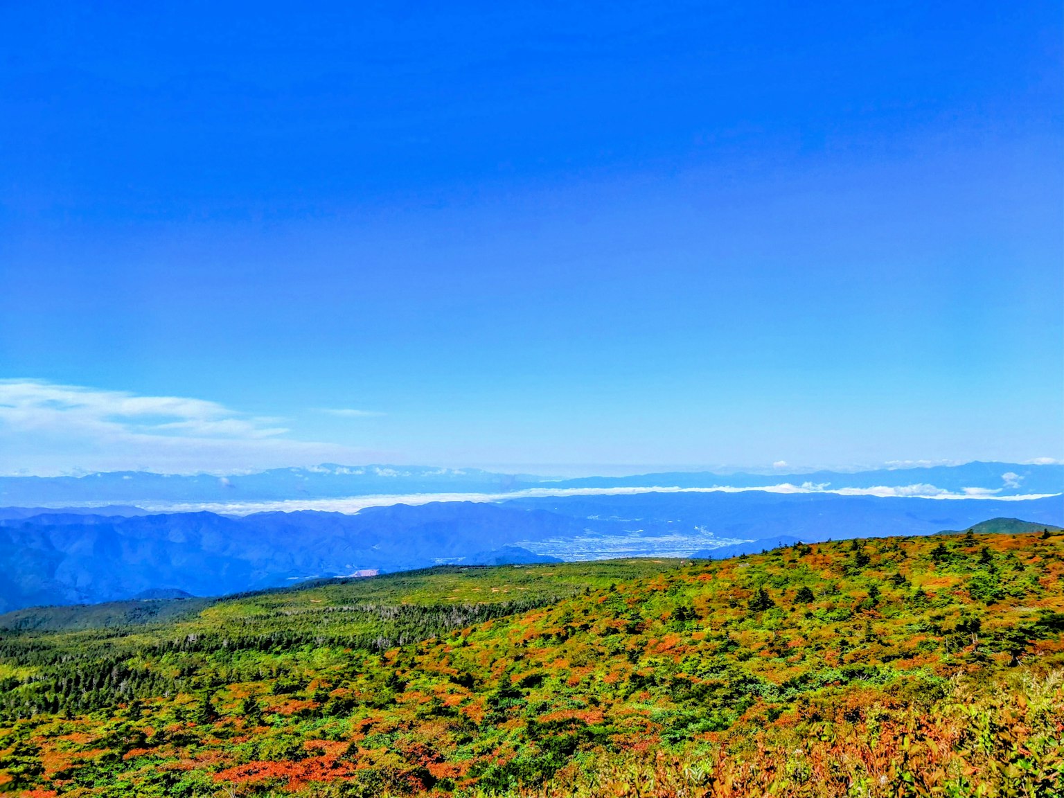 Panoramablick auf grüne Berge unter einem blauen Himmel mit fernen Wolken