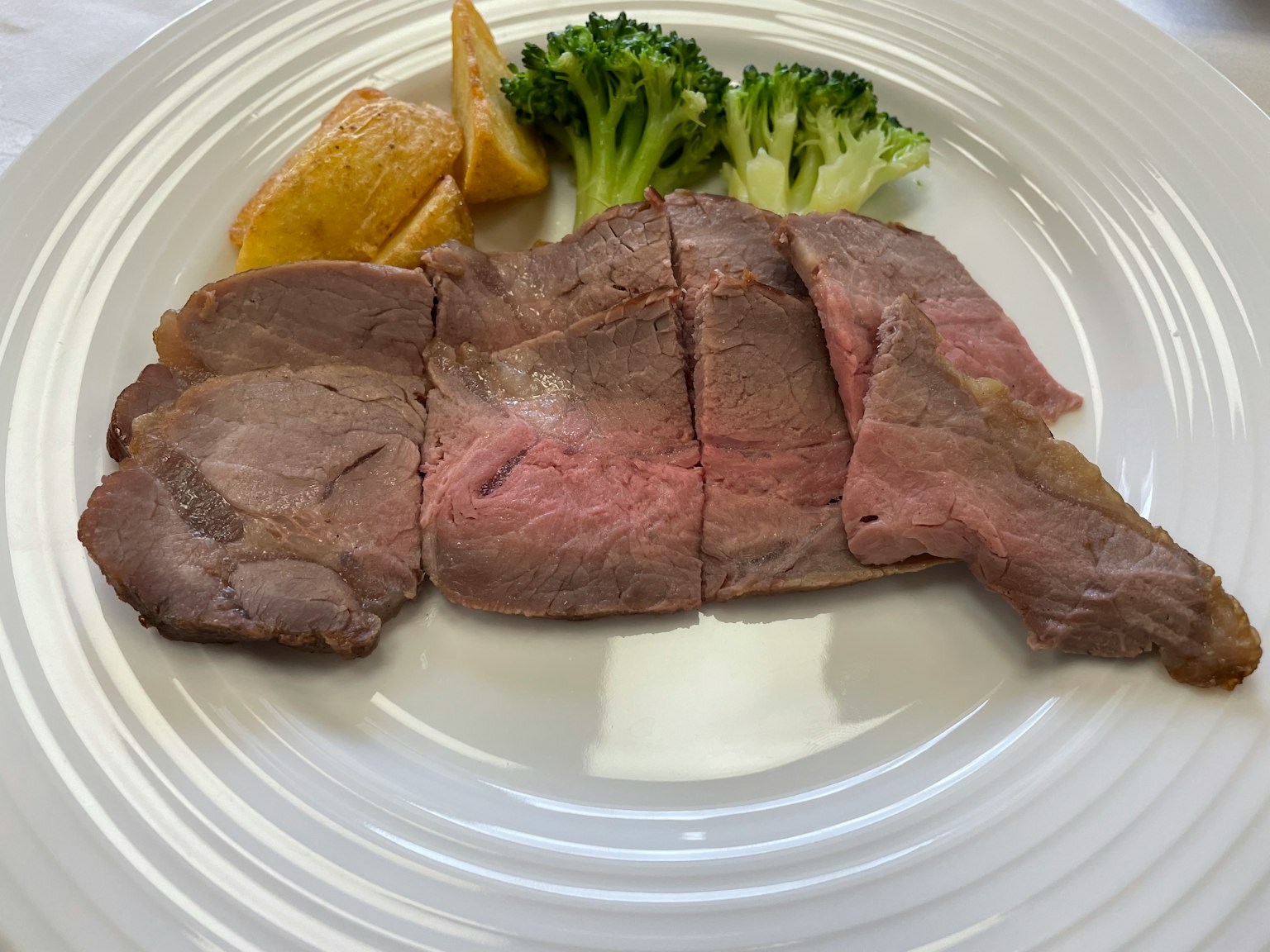 Tranches de rosbif sur une assiette avec du brocoli et des quartiers de pomme de terre