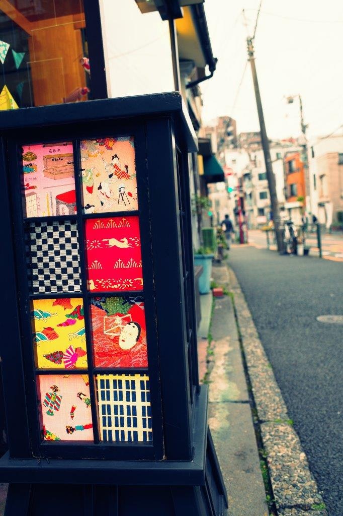 路地の店先に並ぶ色鮮やかなポスターと看板のある街並み